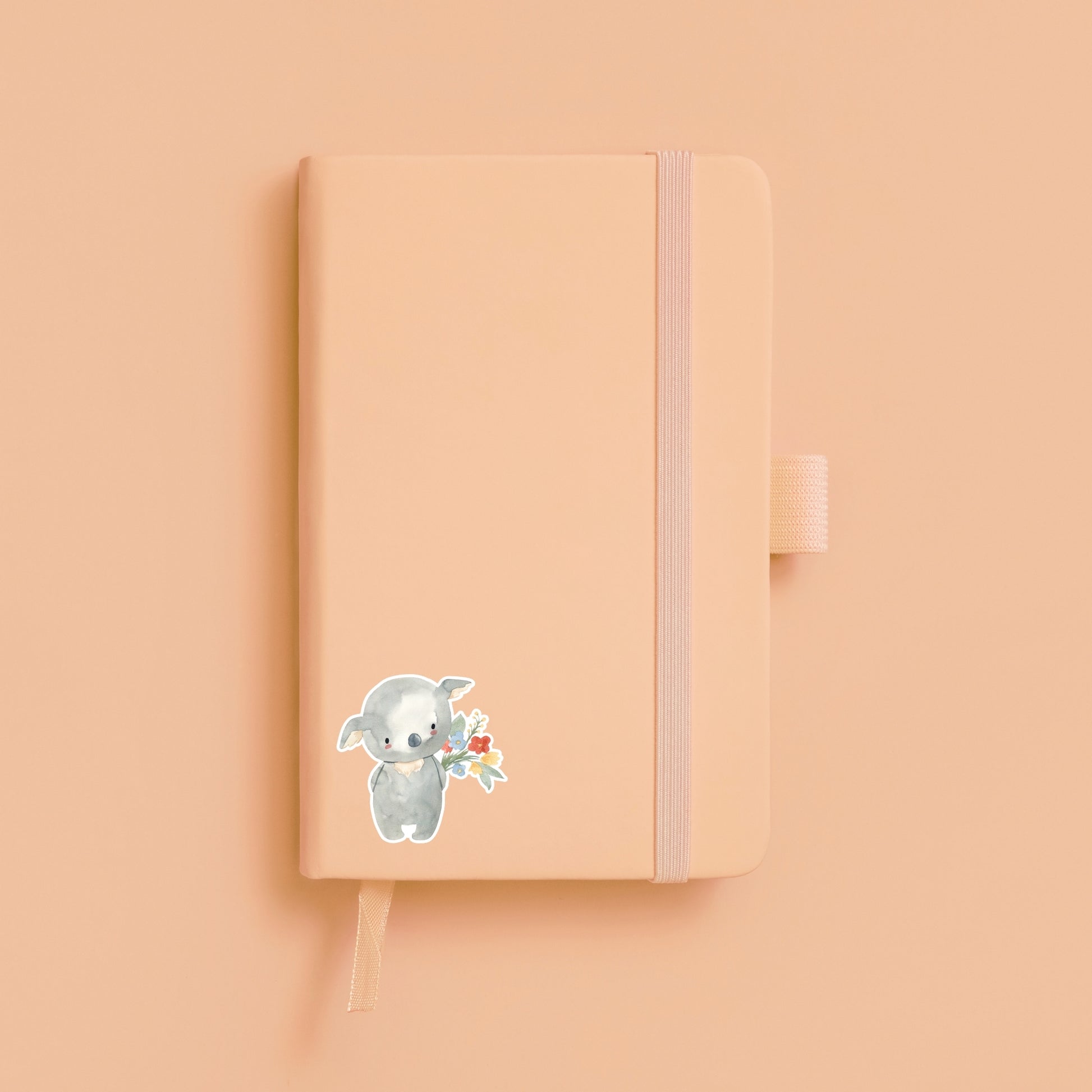 Sticker Koala & Blumen: Ein handgemalter Koala hält Blumen auf einem pinken Notizbuch, ideal zur Dekoration von Bullet Journals, Laptops und Handyhüllen.