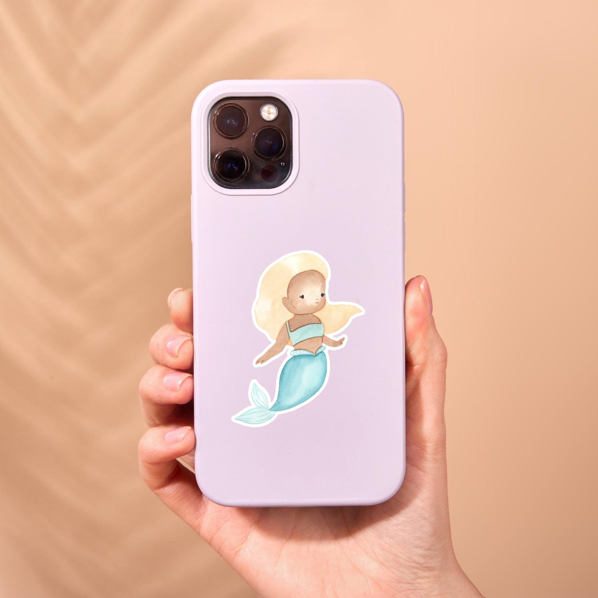 Hand hält eine Handyhülle mit einem handgemalten Sticker Meerjungfrau blond, in zarten Pastelltönen. Ideal für Meerjungfrauen-Fans, spritzfest und langlebig.