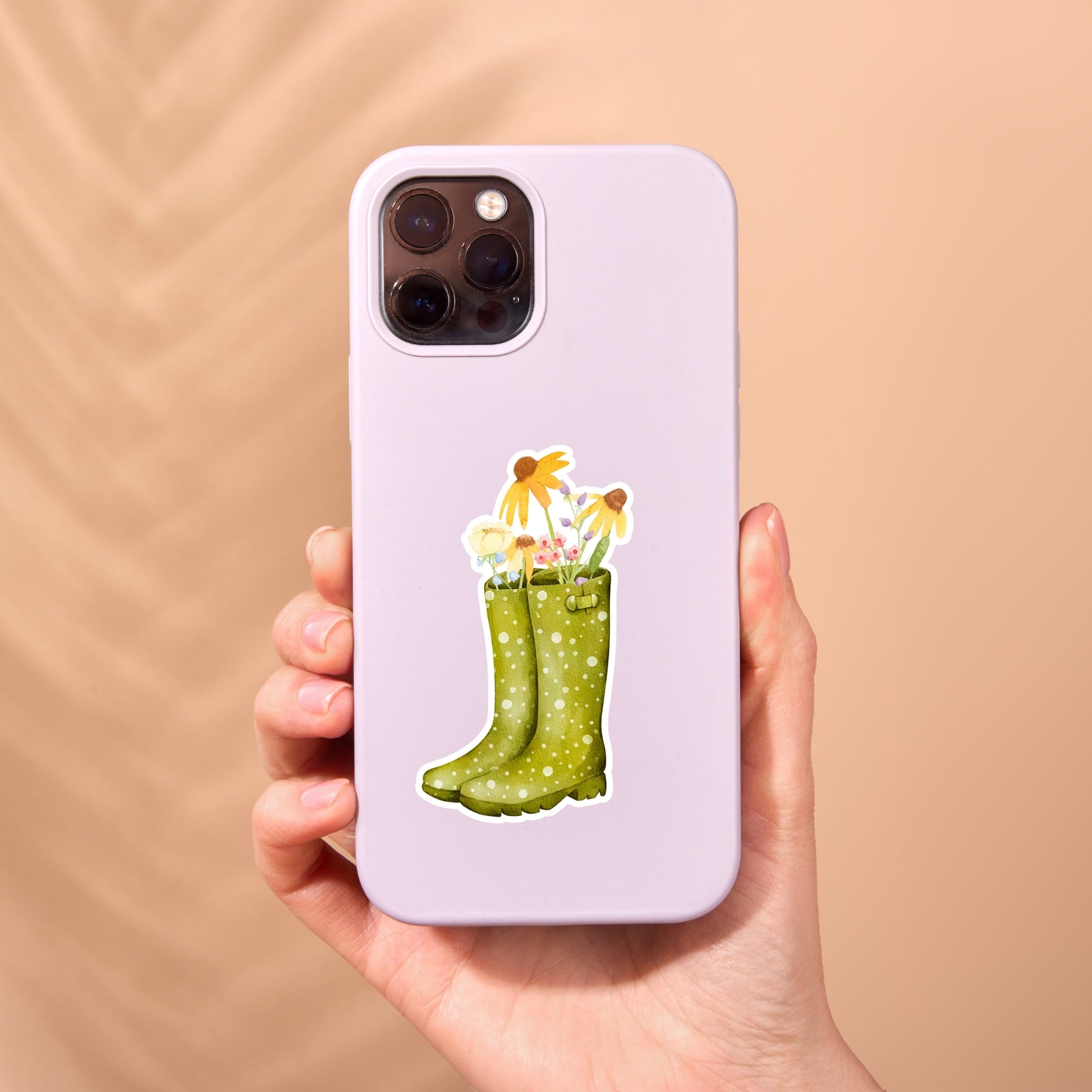 Hand hält Handyhülle mit Sticker Wildblumen, zeigt grüne Gummistiefel und Blumenmotiv. Hochwertiger Vinyl-Sticker, ideal für individuelle Gestaltung und Naturinspiration.