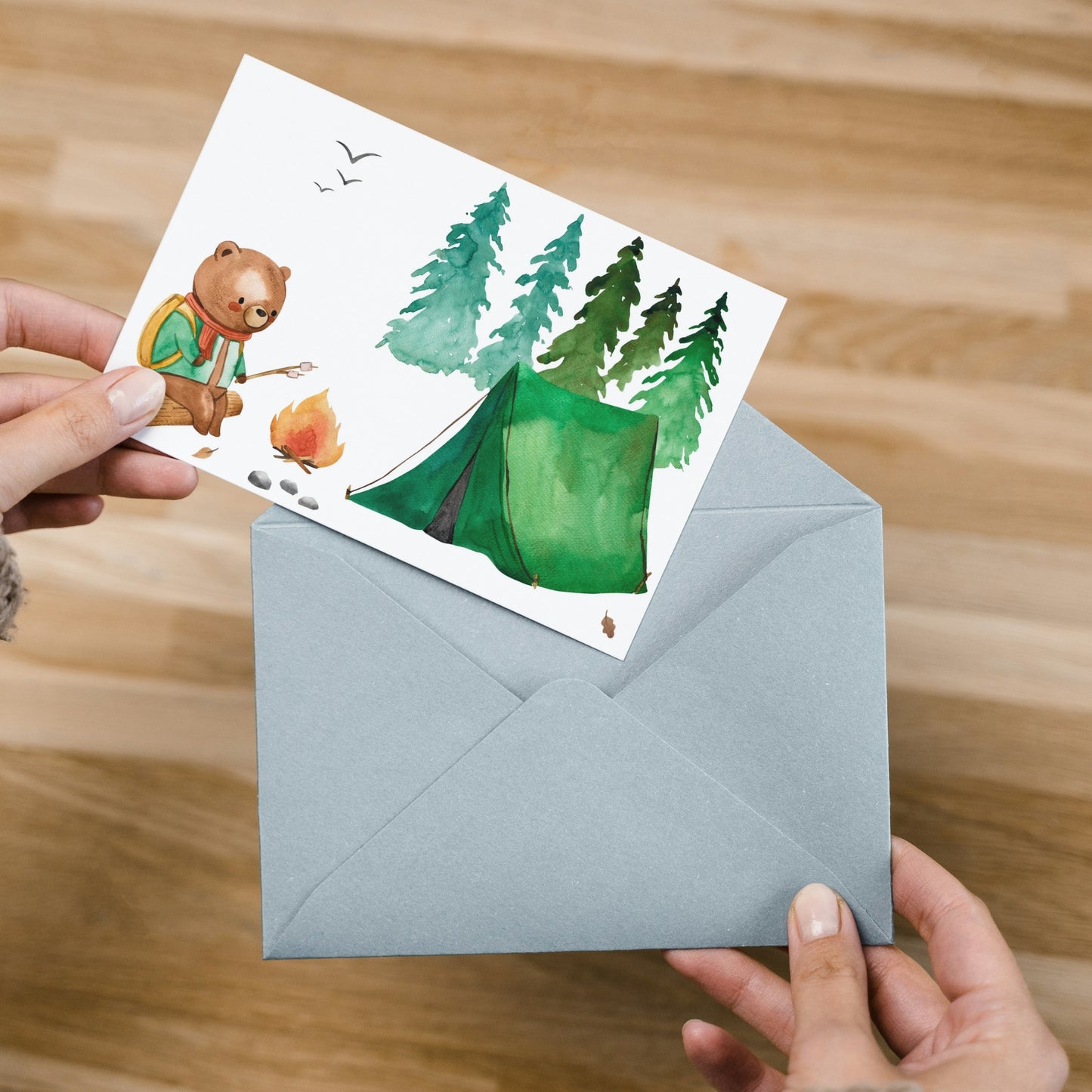 Person hält Karte Bär & Camping A6: niedlicher Bär beim Camping mit Zelt und Lagerfeuer, auf hochwertigem, matt bedrucktem Naturpapier.