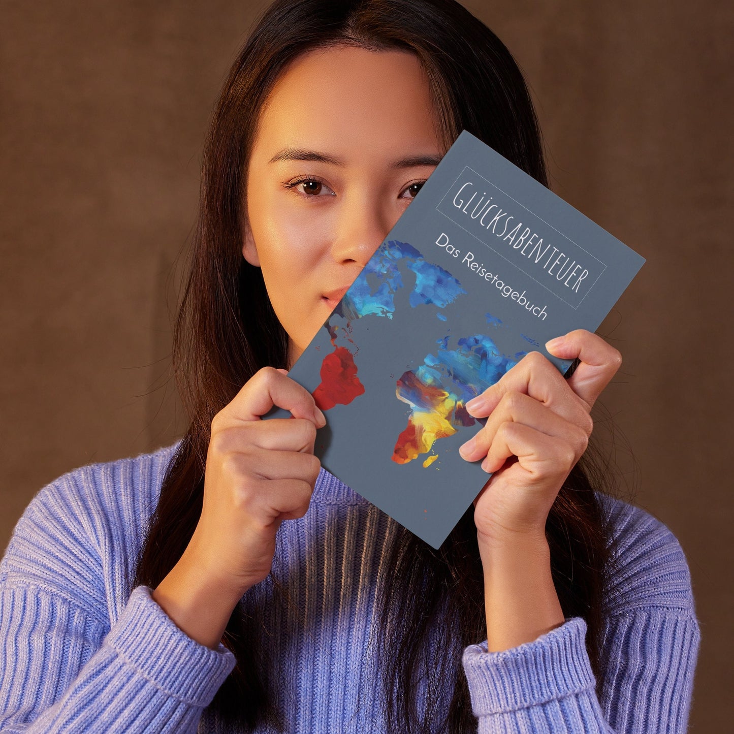 Person hält Reisetagebuch A5 Softcover mit bunter Weltkarte. Ideal zum Planen und Festhalten von Reiseerinnerungen.