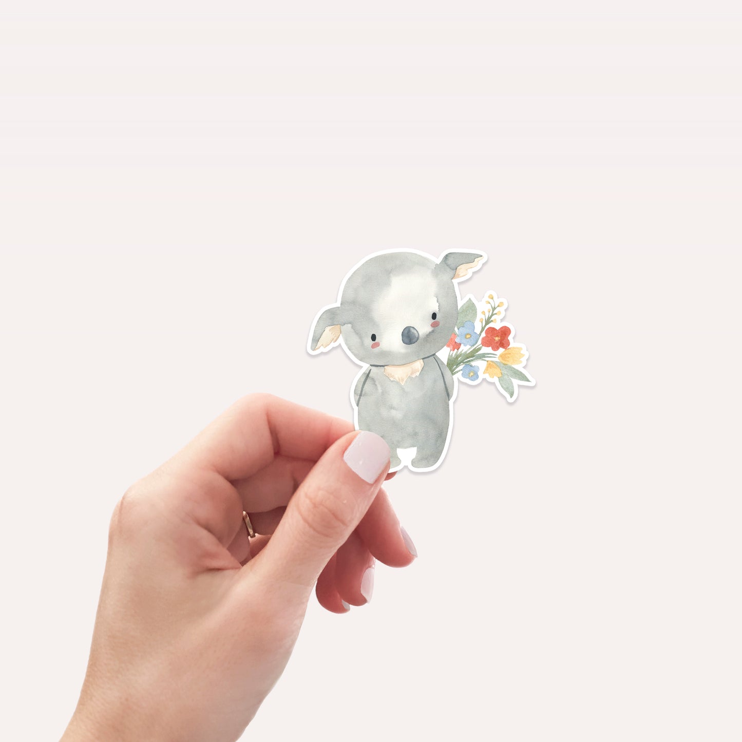 Hand hält den Sticker Koala & Blumen: Ein handgemalter Vinyl-Aufkleber mit Koala und Blumenstrauß, ideal für Bullet Journals, Laptops oder als Geschenk.