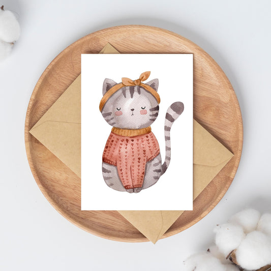 Karte Katze Vintage A6: Handgezeichnete Karte mit einer Katze in einem Pullover und mit Schleife, auf einer Holzplatte präsentiert. Ideal als Gruß- oder Geburtstagskarte.