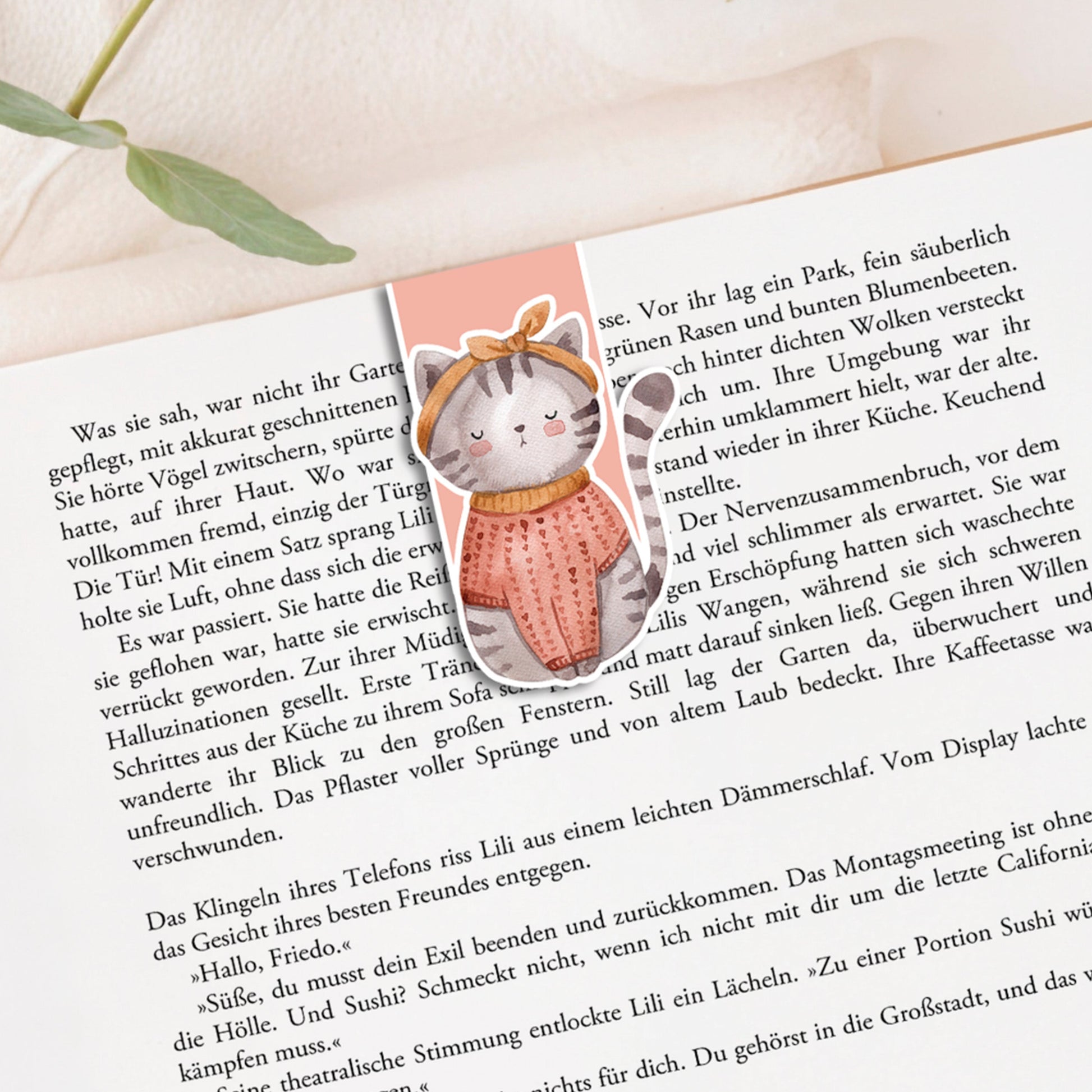 Magnetisches Lesezeichen Katze auf einem Buch; zeigt eine handgemalte Katze mit Schal und Schleife. Hergestellt aus 200g Papier, versiegelt mit Vinyl.
