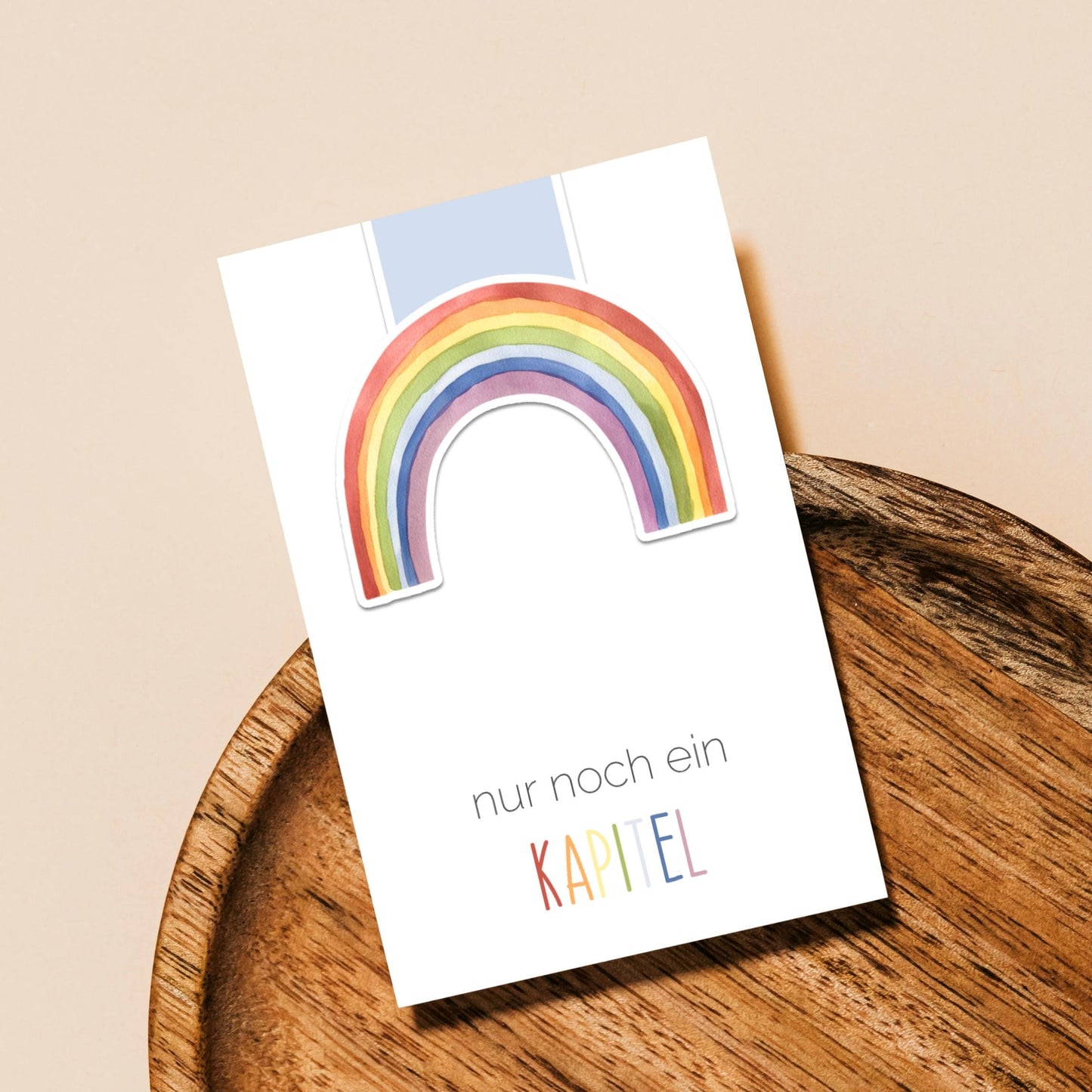 Magnetisches Lesezeichen Regenbogen blau, handgemalt, aus 200g mattem Papier mit Vinylschutz, ca. 6x5,5cm groß, ideal als langlebiges Geschenk für Buchliebhaber. Auf Holztablett präsentiert.