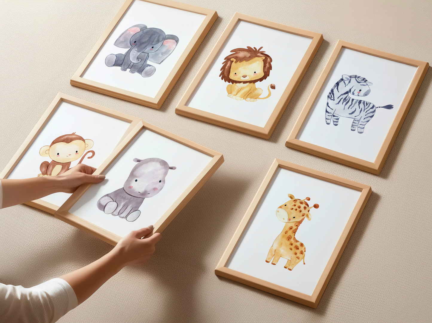 Posterset Safari: Sechs Aquarelldrucke mit Elefant, Löwe, Zebra, Affe, Hippo, Giraffe in Holzrahmen, ideal für Kinderzimmer. Hände arrangieren zwei Bilder.