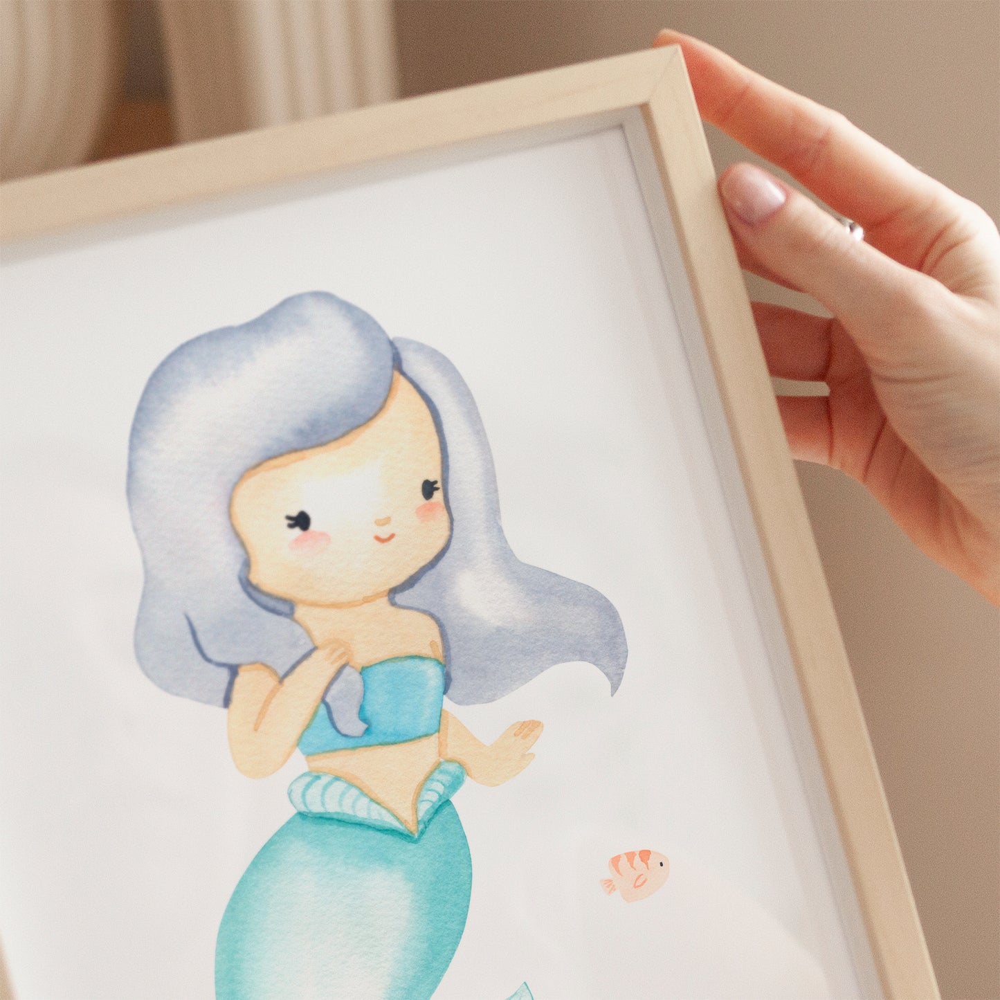 Poster Meerjungfrau & Fisch A3 & A4 zeigt eine Hand, die ein Bild einer Meerjungfrau hält, ideal als Kinderzimmerdeko auf hochwertigem, mattem Naturpapier.