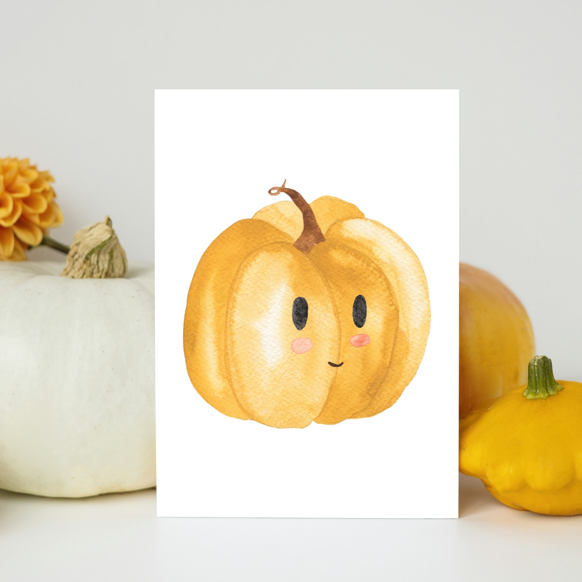 Poster für Kinder mit einer Illustration von einem fröhlichen orangefarbenen Kürbis mit lächelndem Gesicht in Größe A5. Das Bild lehnt an echten Kürbissen. Perfekt für Herbst-Dekoration im Kinderzimmer.