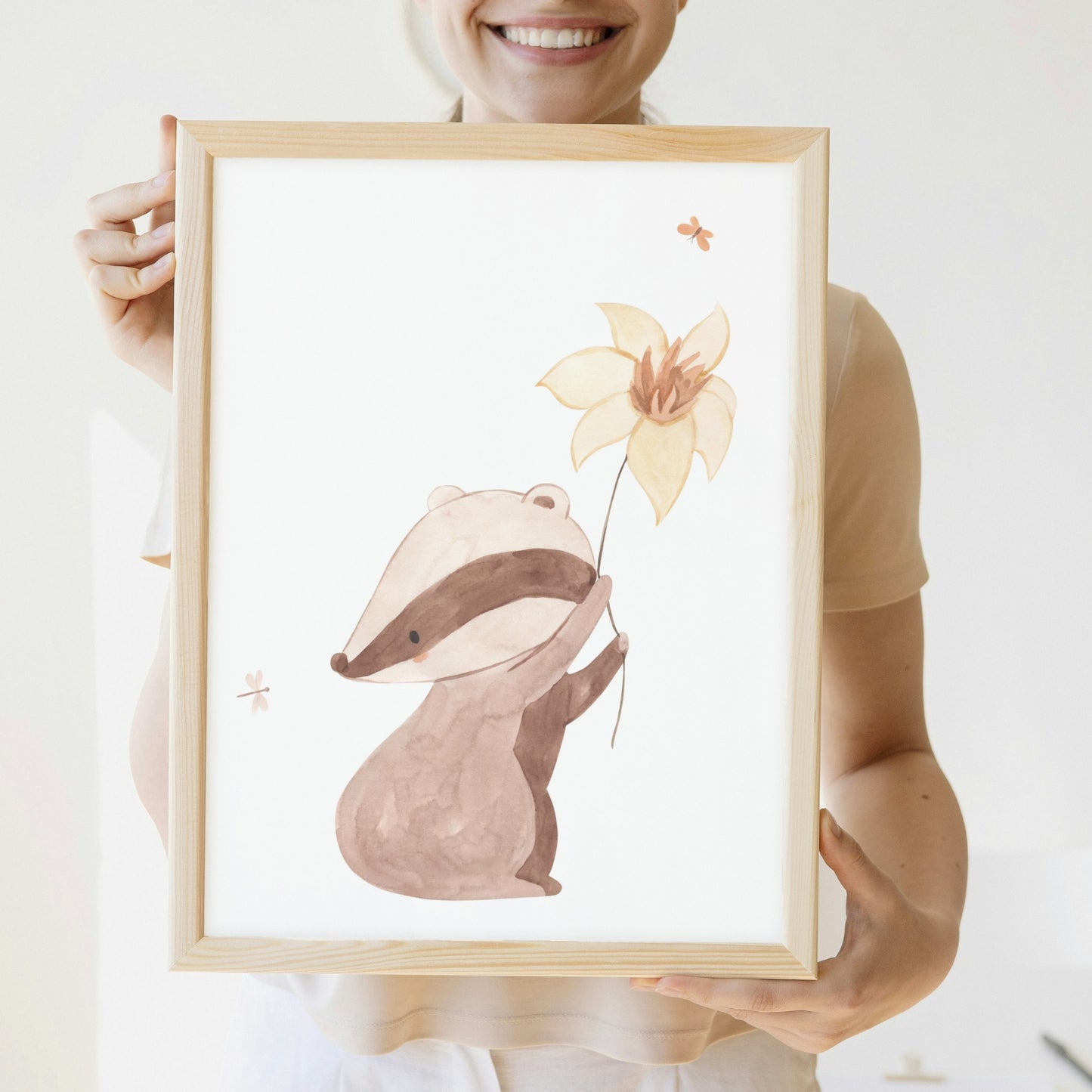 Person hält Poster Dachs A4 & A3: Aquarell-Dachs, der eine Blume hält, ideal für das Kinderzimmer, auf hochwertigem, mattem Naturpapier gedruckt.