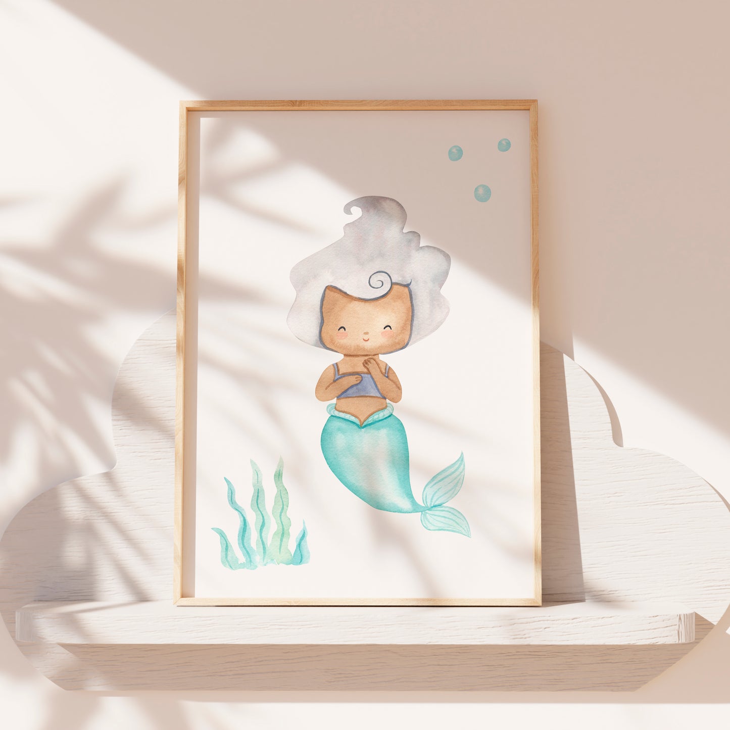 Poster Meerjungfrau silber A3 & A4, gerahmt und auf einem Regal stehend, zeigt eine süße Meerjungfrau im Cartoon-Stil, ideal für Kinderzimmerdeko.