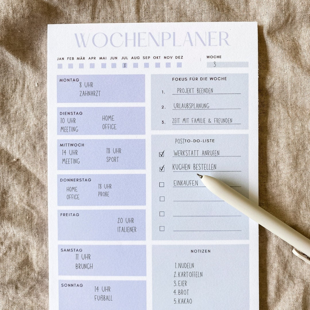 Wochenplaner Hellblau A5 Block: Ein Stift liegt auf einem Blatt Papier des Wochenplaners, ideal für Termine, Notizen und To-Do-Listen.