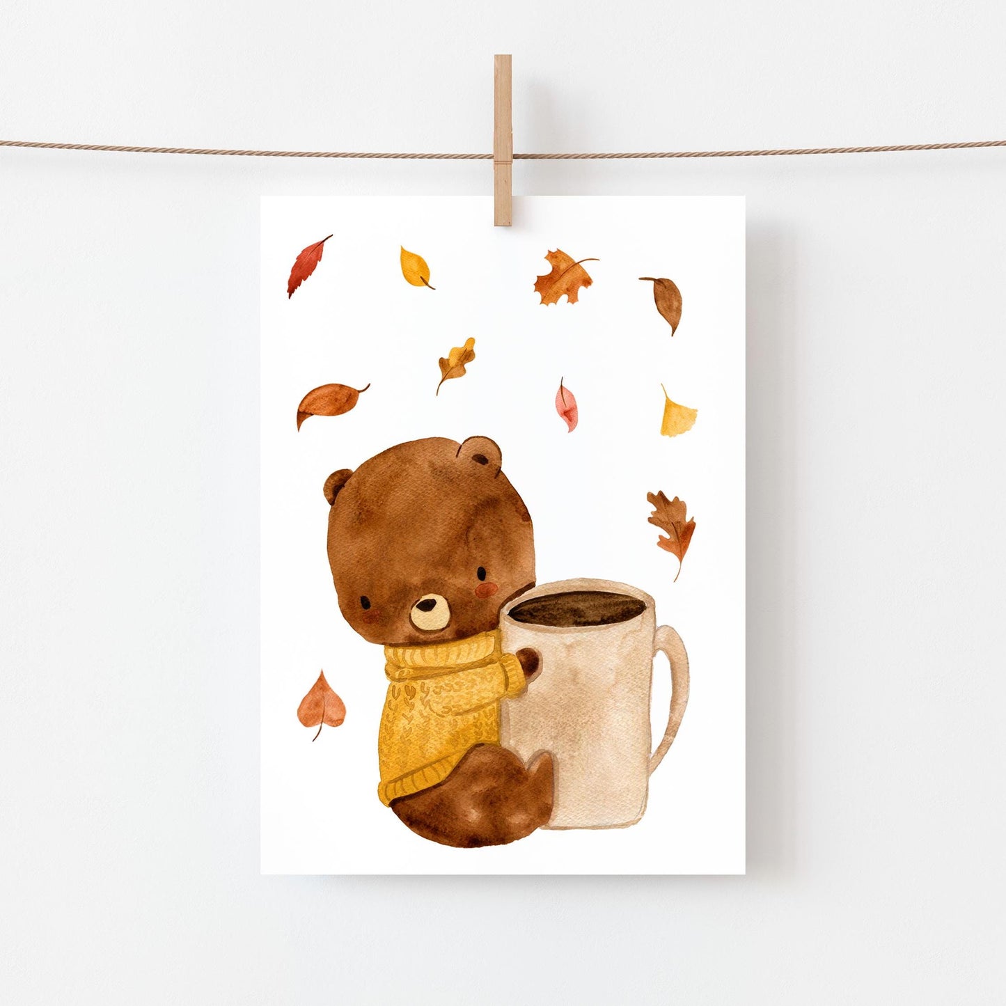 Postkarte mit Aquarell-Bär, der eine Tasse Kaffee hält, umgeben von Herbstlaub. Gedruckt auf hochwertigem, mattem Naturpapier. Größe: A6.