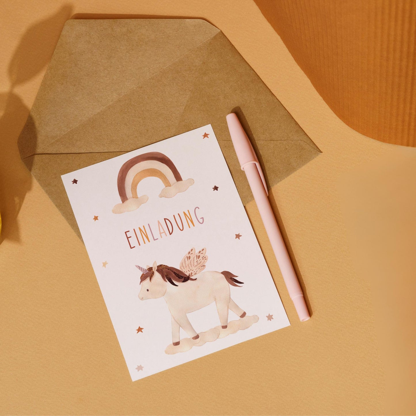 Einladung Kindergeburtstag Einhorn Boho A6: Karte mit Einhorn-Design, liegt mit einem Stift auf braunem Umschlag, aus hochwertigem 300g Naturpapier, einfach auszufüllen.