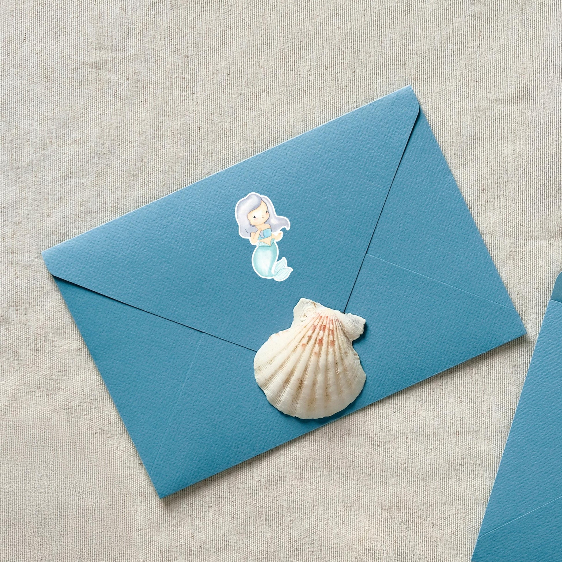 Sticker Meerjungfrau grau: Blauer Umschlag mit Muschel und Meerjungfrau-Sticker, handgefertigt, spritzfest, ideal für Bullet Journals, Hefte oder Handyhüllen.