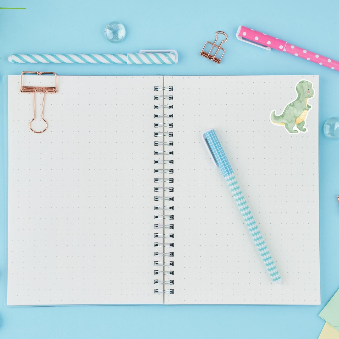 Sticker Dinosaurier Tyranno auf einem Notizbuch mit Stift und Büroklammern. Handgefertigter Vinyl-Aufkleber, ideal für Bullet Journals oder Schulhefte.