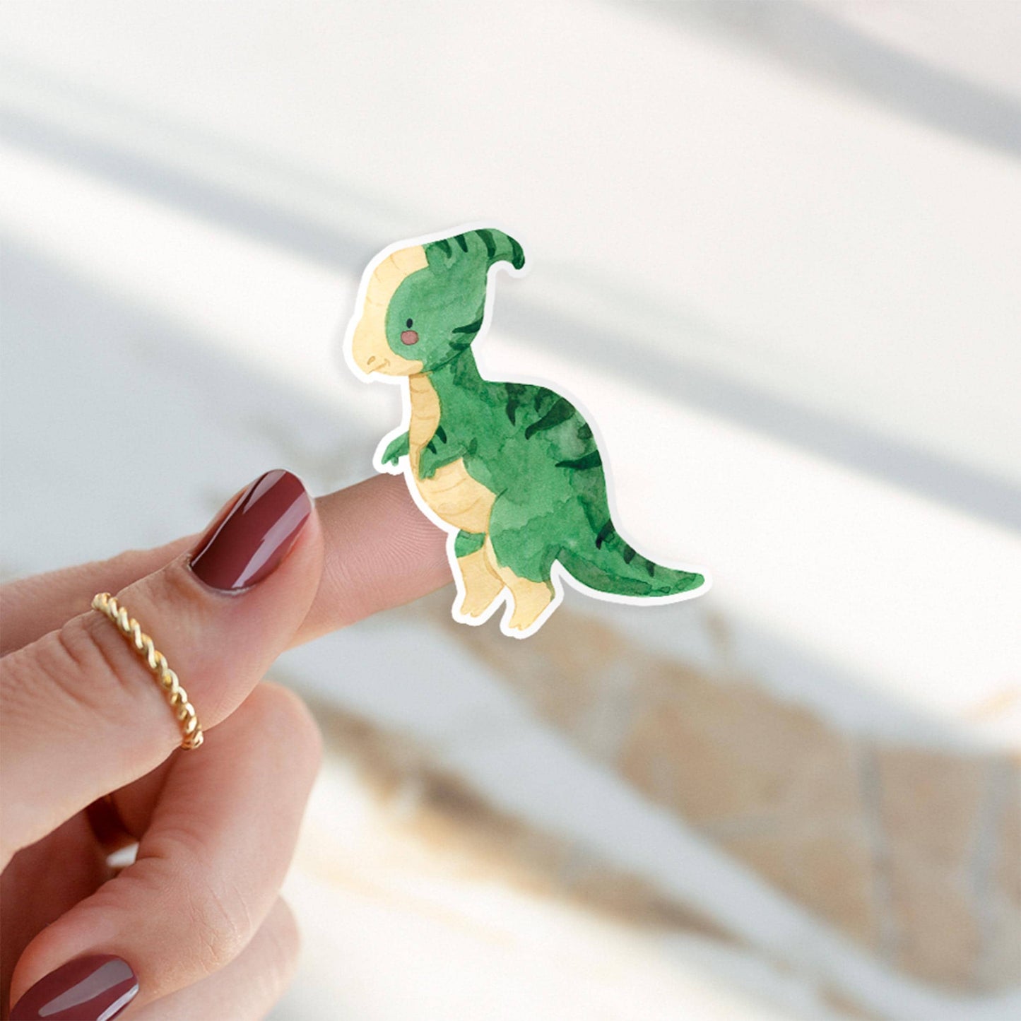 Person hält Sticker Dinosaurier Parasauro auf dem Finger, handgemalter Vinylaufkleber, ideal für Bullet Journals oder Handys, spritzfest und langlebig.