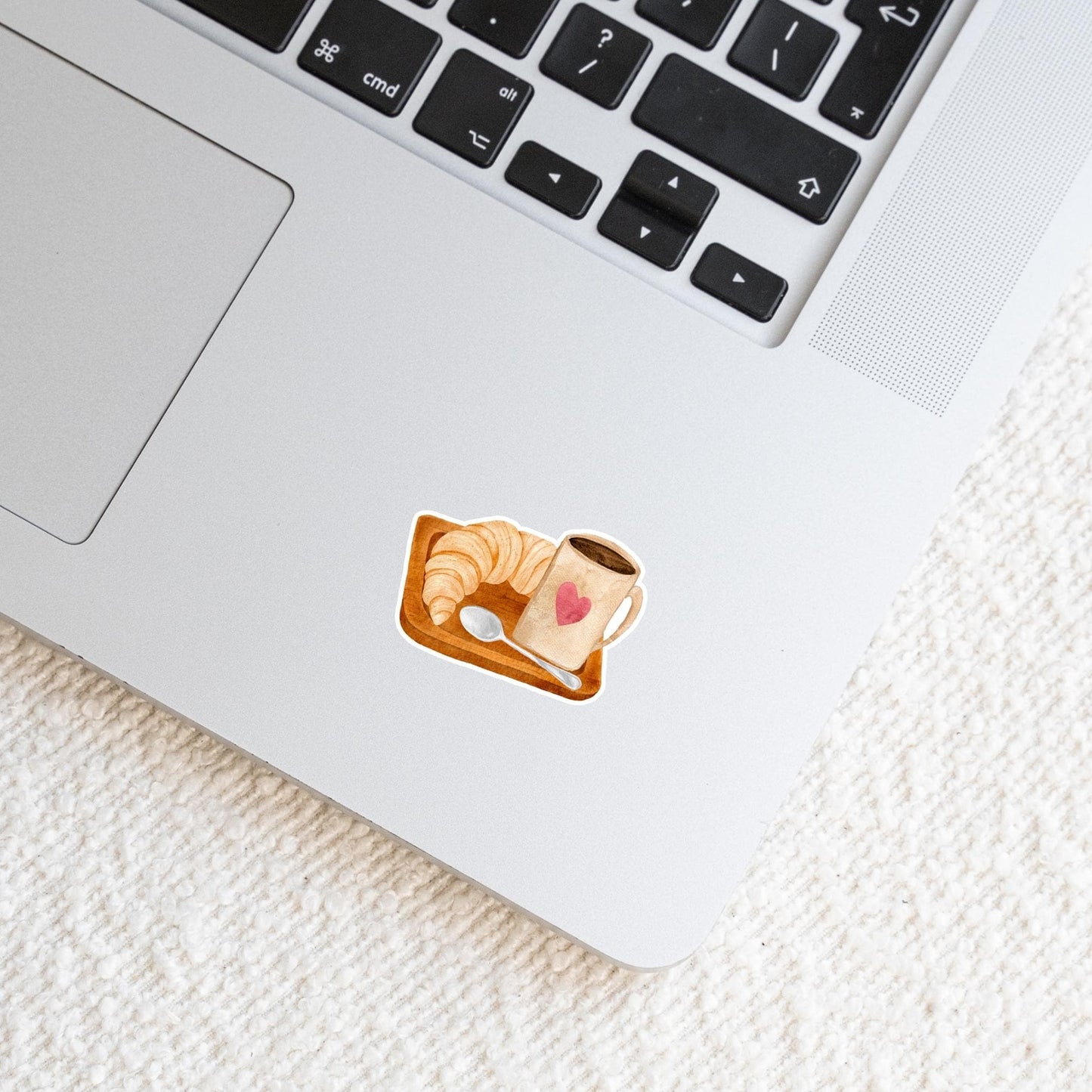 Sticker Frühstück: Ein Laptop mit einem handgefertigten Kaffee- und Croissant-Sticker aus Vinyl, ideal für eine individuelle Gestaltung und langlebigen Schutz.