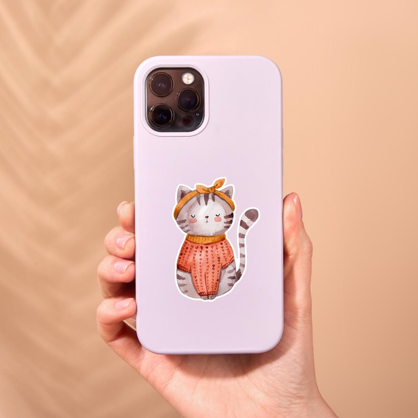 Sticker Katze: Eine Hand hält eine Handyhülle mit einem Cartoon einer Katze im Vintage-Stil, die einen Pullover trägt. Perfekt für Katzenliebhaber.
