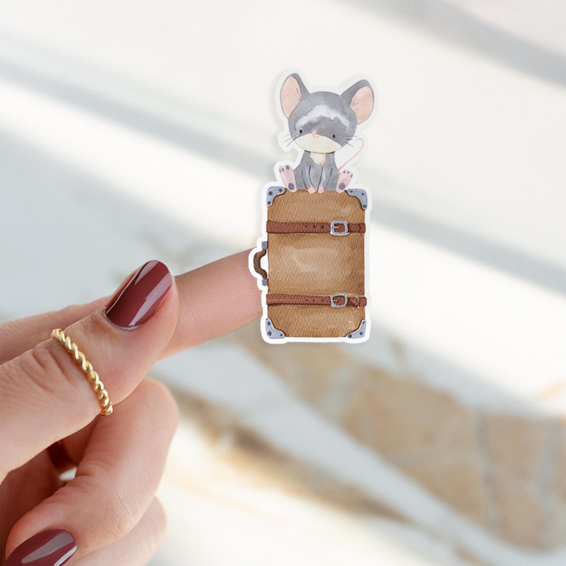 Sticker Maus & Koffer: Ein Finger zeigt einen handgemalten Vinyl-Sticker mit einer Maus auf einem Koffer. Ideal für Bullet Journals und Handys.