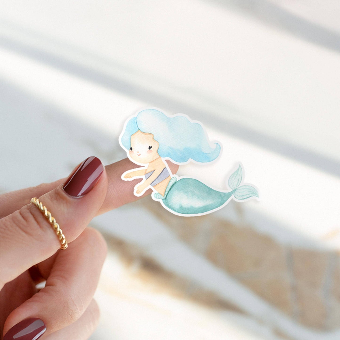 Einschulung Geschenk-Set Meerjungfrauen: Nahaufnahme eines Fingers mit Meerjungfrau-Illustration, umgeben von goldener Kette, repräsentiert das zauberhafte Schulkind-Set.