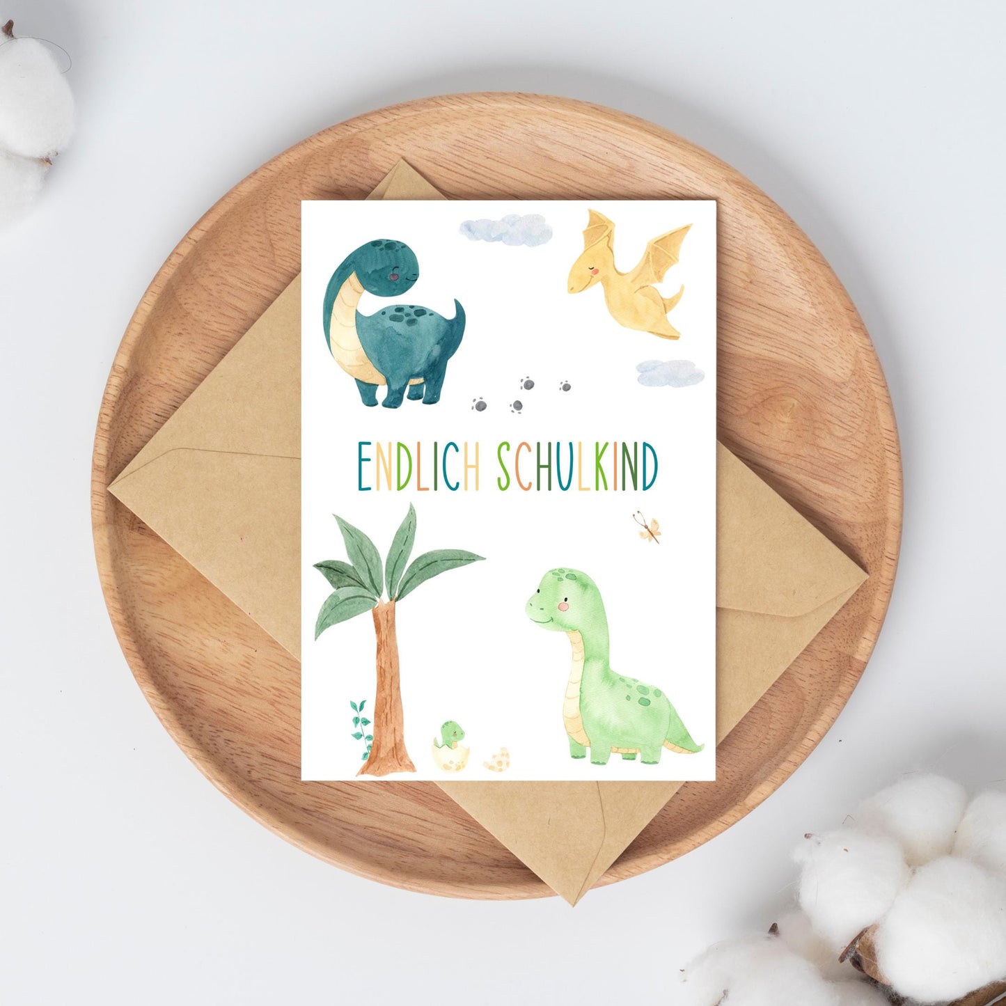 Einschulung Geschenk-Set Dinosaurier: Karte auf Teller mit Dinosaurier-Illustrationen. Perfekt für den ersten Schultag, inklusive laminiertem Stundenplan und Lesezeichen.