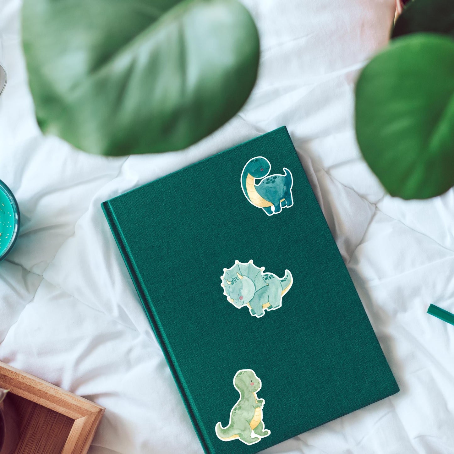 Sticker Dinosaurier dunkelgrün auf grünem Buch mit Cartoon-Dinosaurier. Hochwertiger Vinyl-Sticker, ideal für Bullet Journals oder Laptops. Perfekt für Dino-Fans.