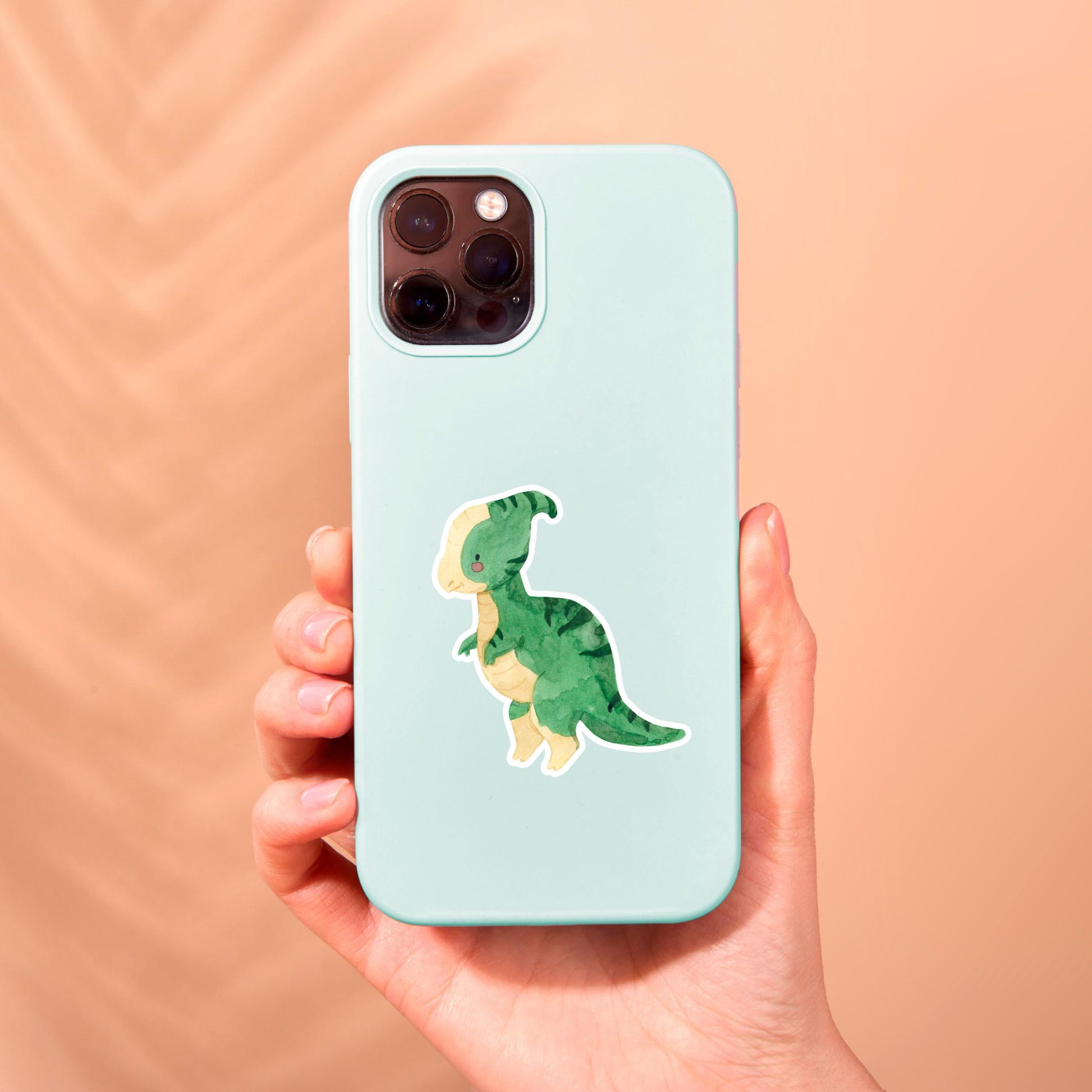Hand hält eine Handyhülle mit dem Sticker Dinosaurier Parasauro, einem handgemalten, wasserfesten Vinyl-Aufkleber, ideal für individuelle Gestaltung und langlebigen Schutz.