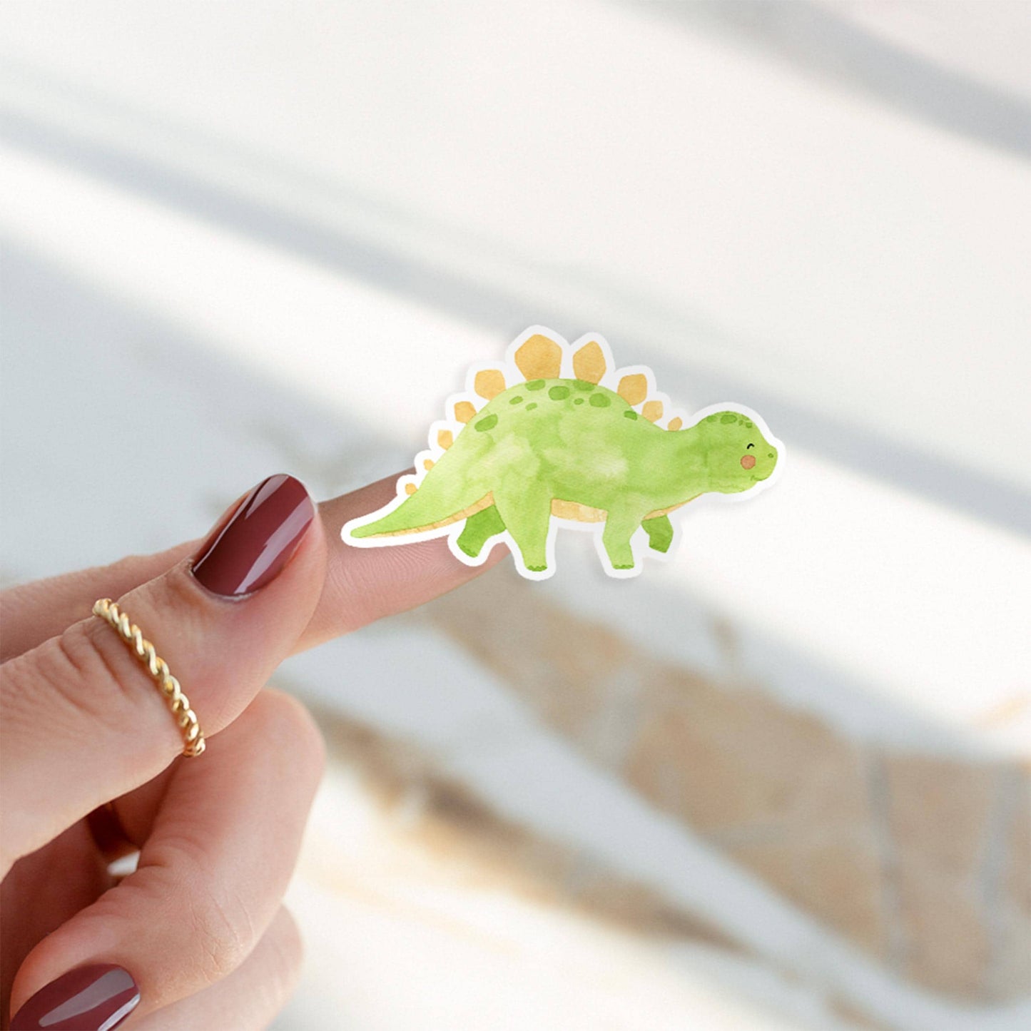 Sticker Dinosaurier Stego: Ein handgemalter Vinyl-Dino-Sticker wird auf einem Finger präsentiert, ideal für kreative Dekorationen wie Bullet Journals oder Hüllen.