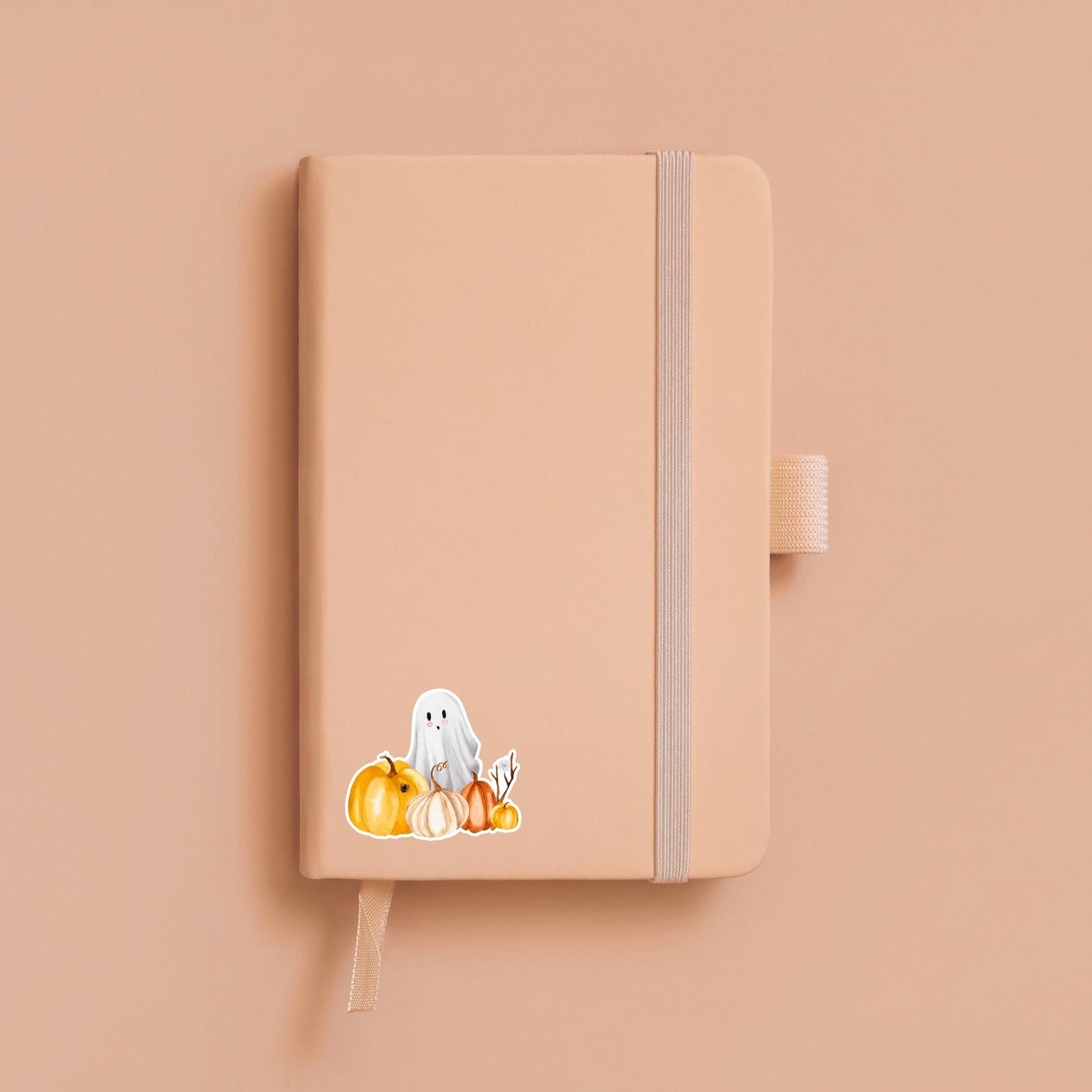 Halloween-Sticker mit handgemaltem Gespenst und Kürbissen auf einem Notizbuch, ideal zur individuellen Gestaltung von Bullet Journals oder als kreatives Bastelaccessoire.
