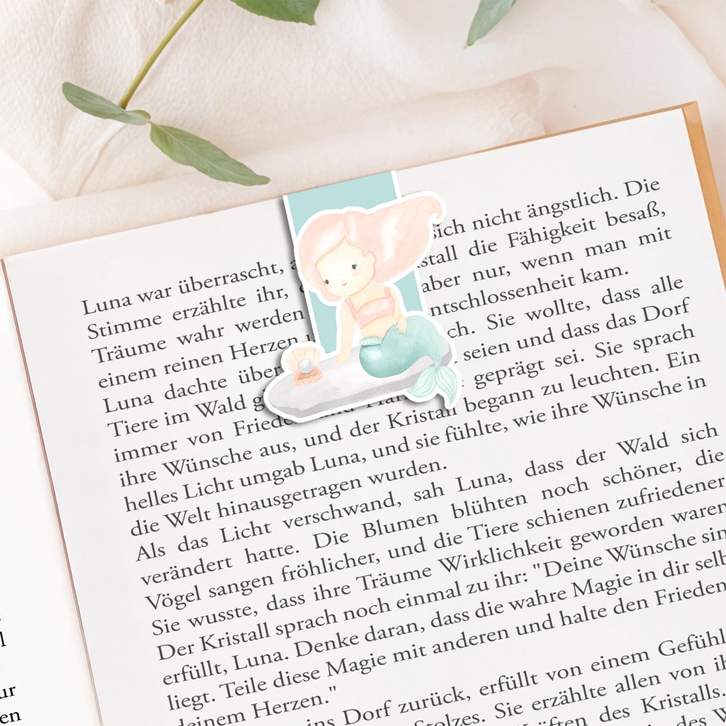 Einschulung Geschenk-Set Meerjungfrauen: Buch mit Meerjungfrau-Illustration, umgeben von Lesezeichen und Stickern im passenden Design für den ersten Schultag.