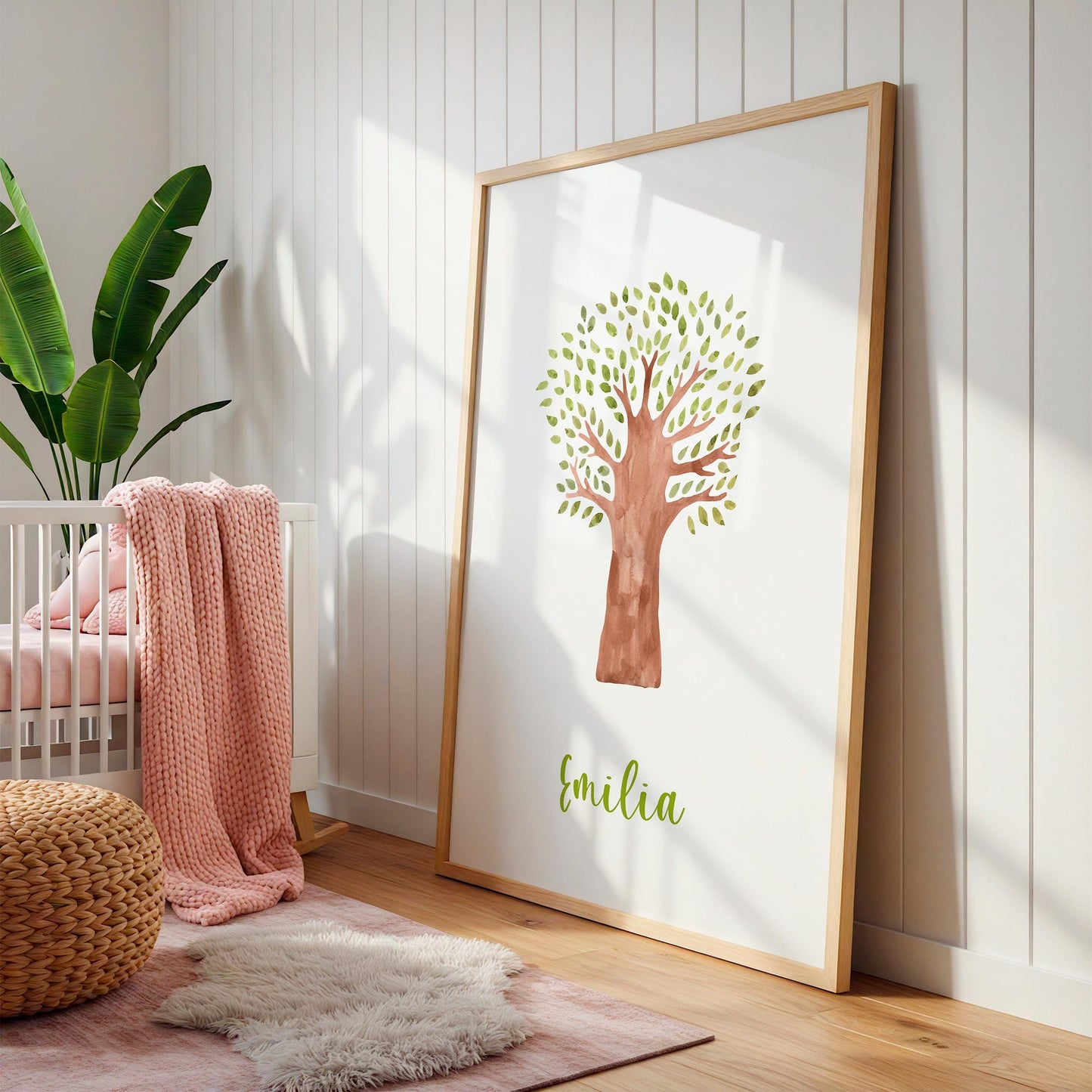 Geburtsposter Baum personalisiert: Ein gerahmtes Poster mit handgemaltem Baum und Name „Emilia“, perfekt für Kinderzimmerdekoration, neben einem weißen Kinderbett arrangiert.