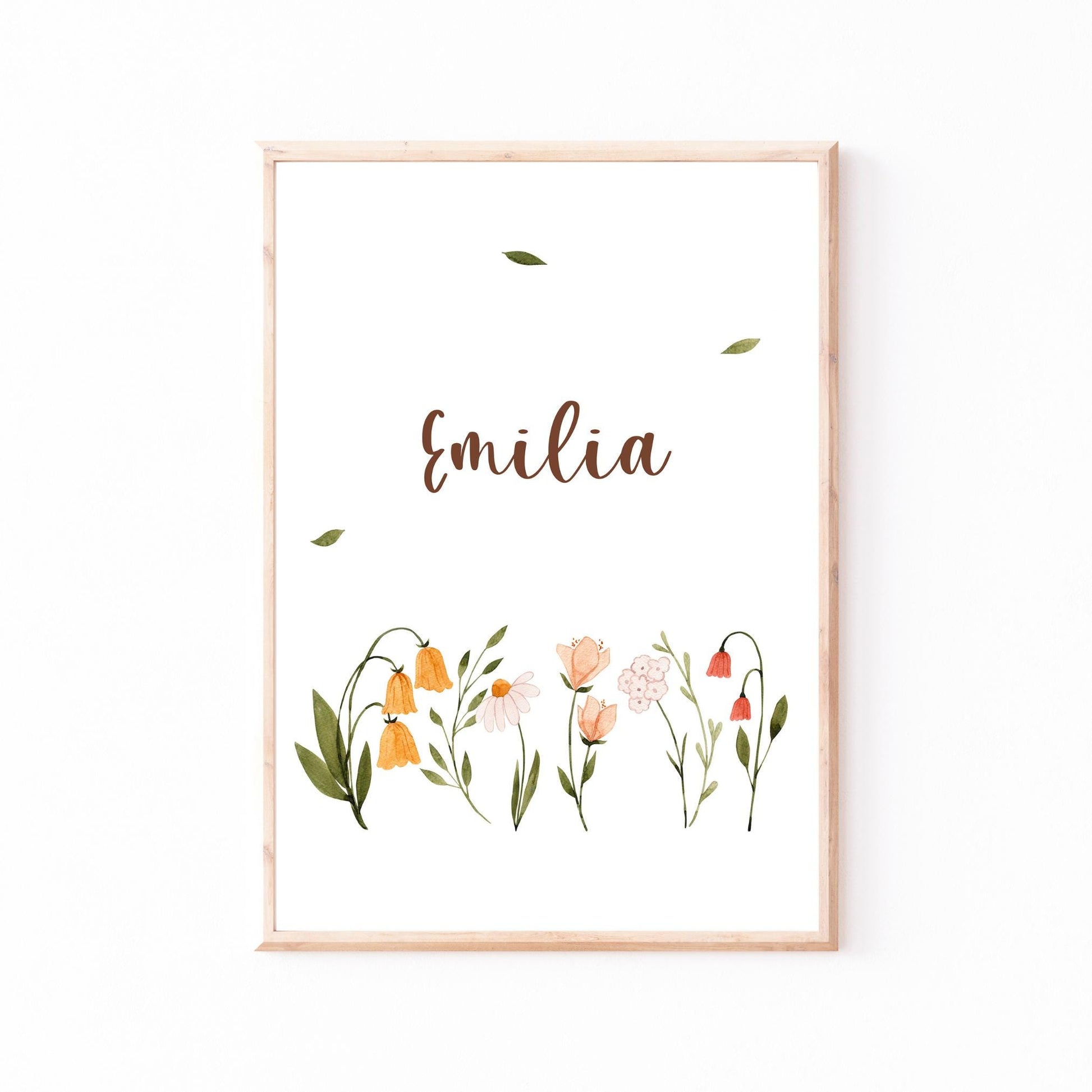 Namensposter personalisiert mit Emilia in brauner Handschrift, umgeben von zarten Aquarell-Wildblumen in Holzrahmen. Ideal als Geschenk zur Geburt oder Taufe.