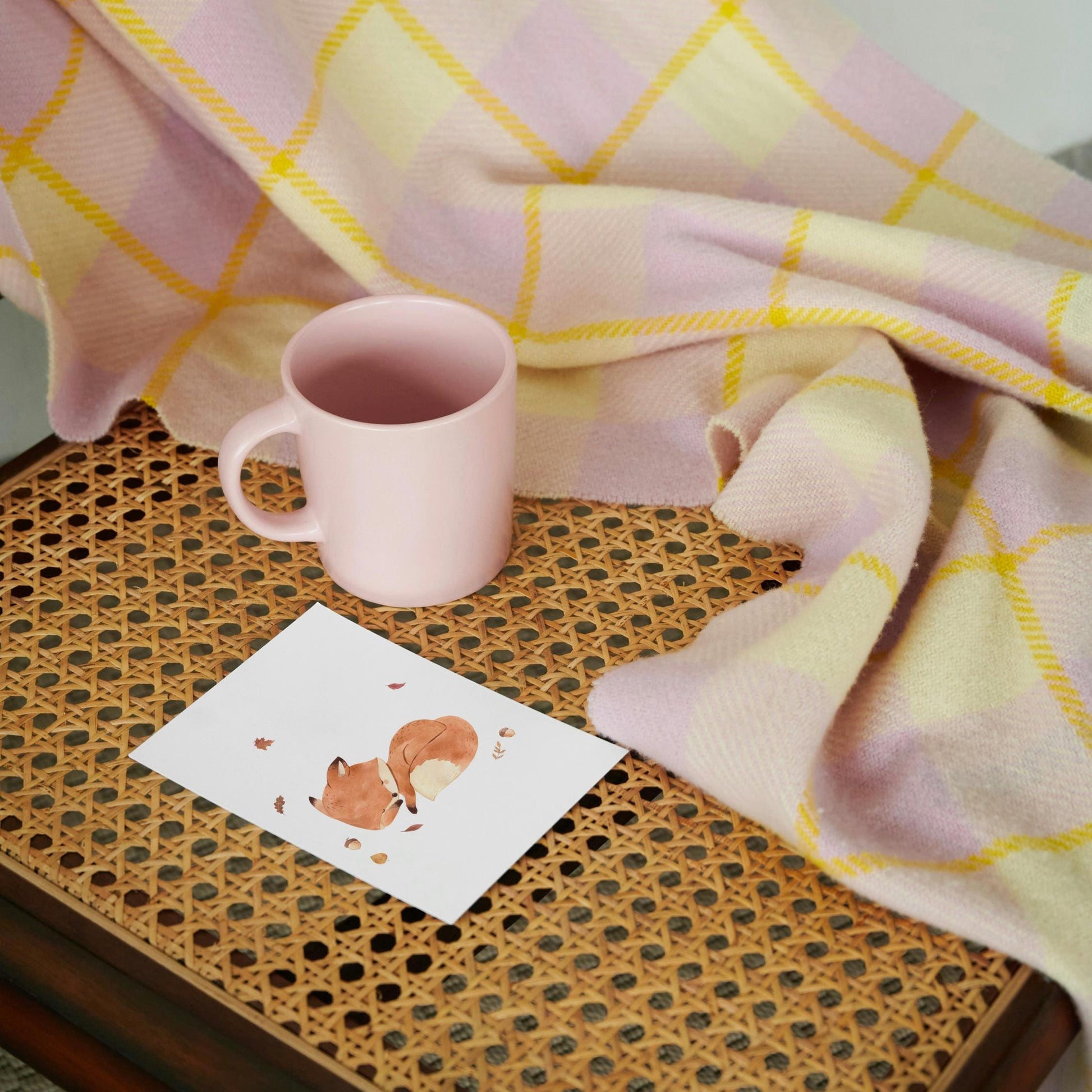 Karte Fuchs & Herbstlaub A6: Eine Postkarte mit Aquarell eines schlafenden Fuchses in Herbstlaub, auf hochwertigem mattem Naturpapier, auf einem Tisch mit Tasse und Decke.