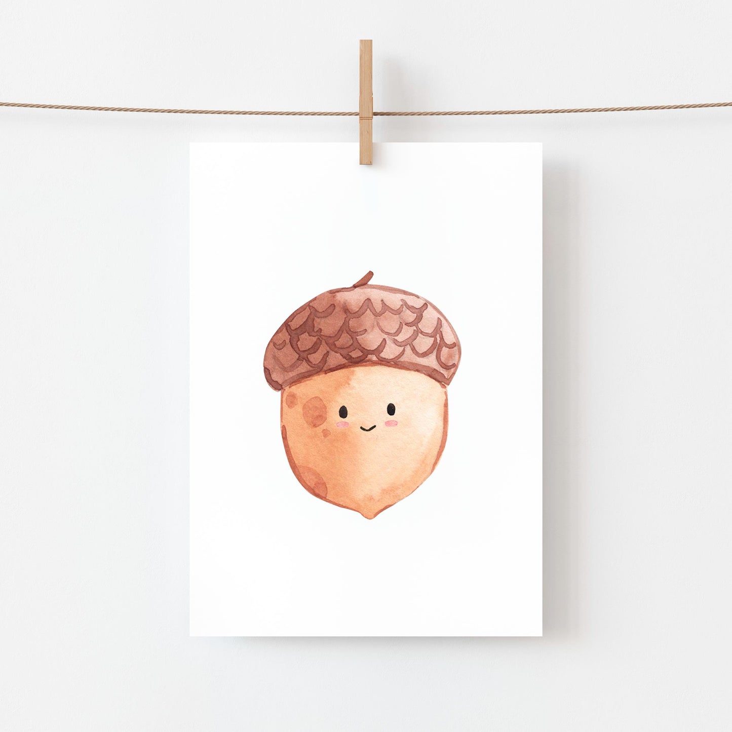 Postkarte Karte Eichel A6 zeigt eine lächelnde Eichel-Illustration, befestigt mit Holzklammer an einem Faden. Ideal als Grußkarte oder herbstliche Dekoration.