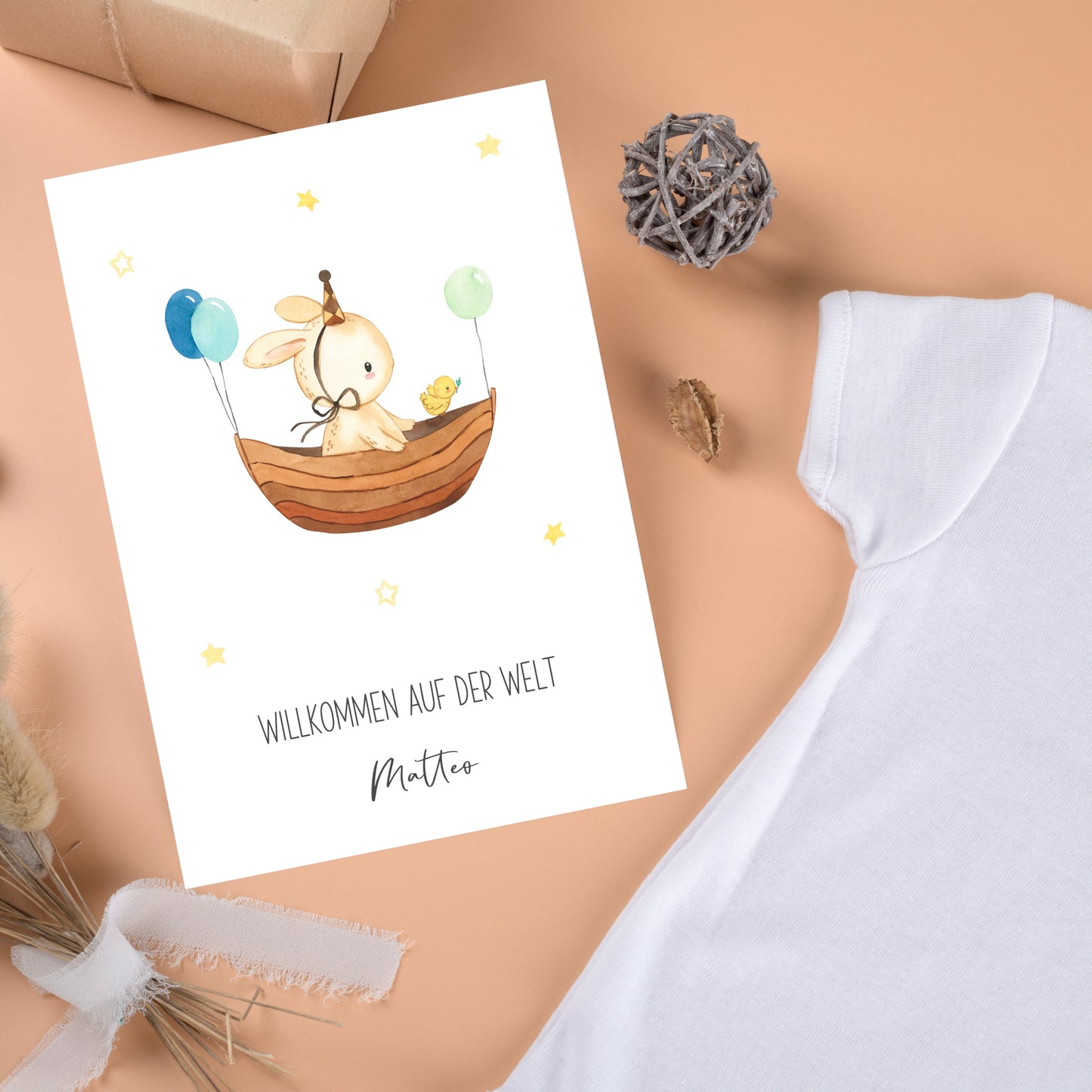 Personalisierte Geburtskarte Hase & Luftschiff A6 mit Wasserfarben-Hase im Boot, Partyhut, Küken, Ballons, und „Willkommen auf der Welt Matteo“-Schriftzug, neben Baby-Body und Geschenken.
