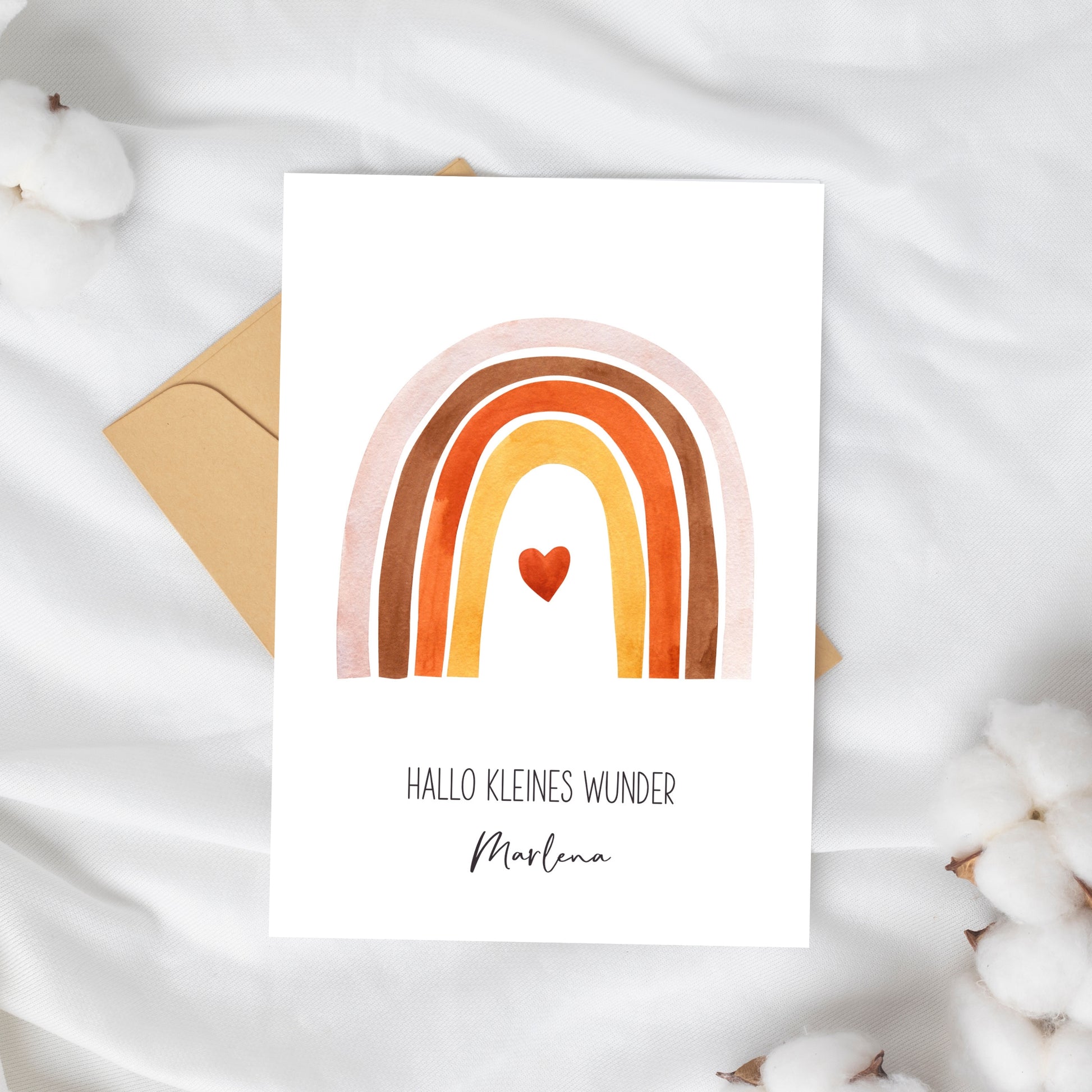 Personalisierte Geburtskarte Regenbogen & Herz A6, zeigt handgemalten Regenbogen mit Herz und Namen Marlena, auf weißem Hintergrund, eingerahmt von Baumwollzweigen, mit braunem Umschlag.