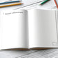 Reisetagebuch Glücksabenteuer A5 Hardcover: Aufgeschlagen auf Tisch mit Stiften, ideal zum Planen und Festhalten von Reiseerinnerungen, mit Packlisten, Budgetplaner und freien Gestaltungsmöglichkeiten.