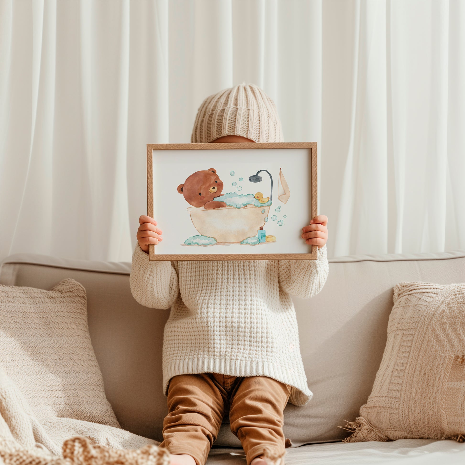 Kind hält gerahmtes Poster Bär in Badewanne A3&A4 mit Bär in Badewanne-Motiv. Perfekt für Kinderbad-Dekor, gedruckt auf hochwertigem Naturpapier.