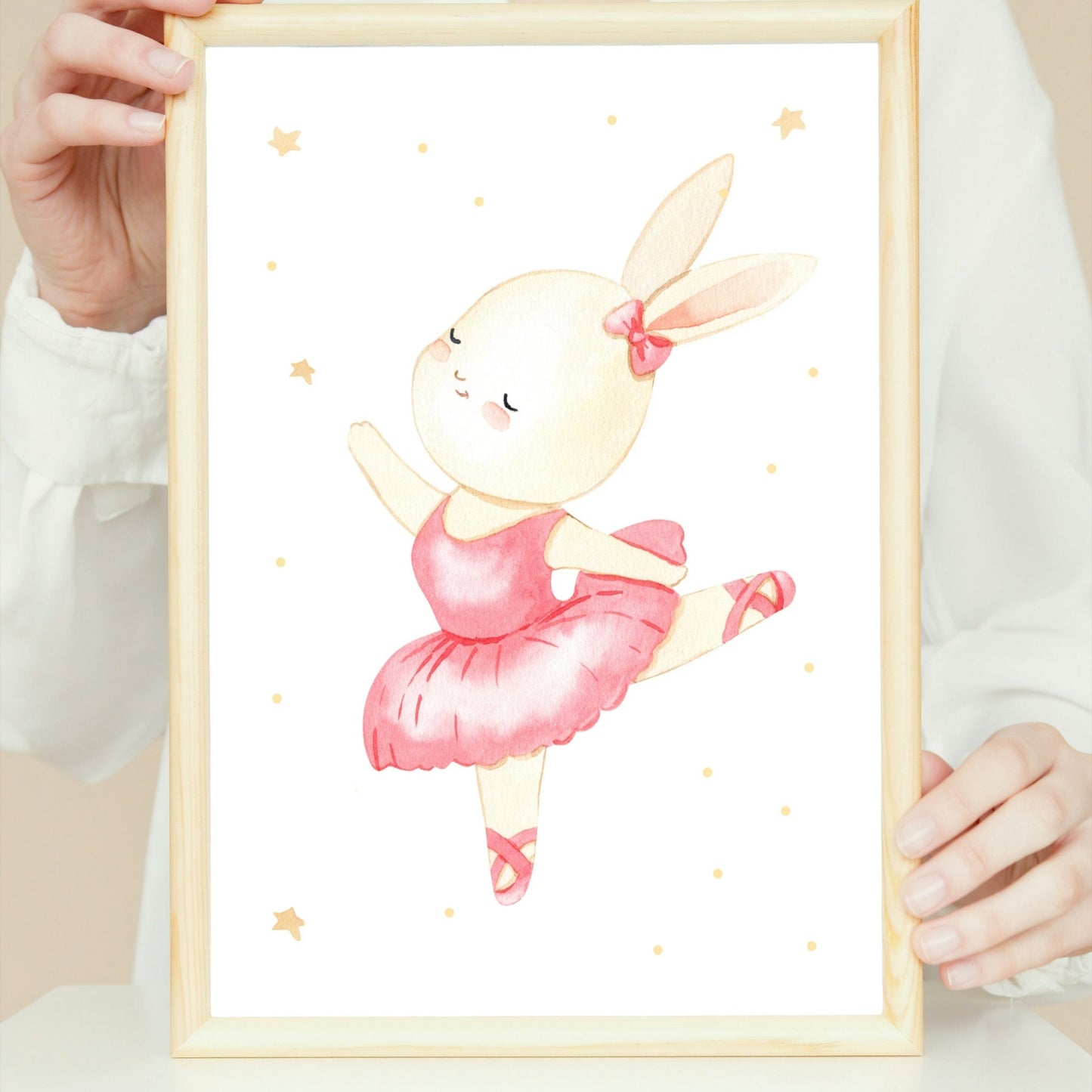 Poster Ballerina Hase Sprung A4 & A3: Eine Person hält ein Aquarellbild. Hase in einem rosa Tutu, perfekt für Kinderzimmerdekoration.