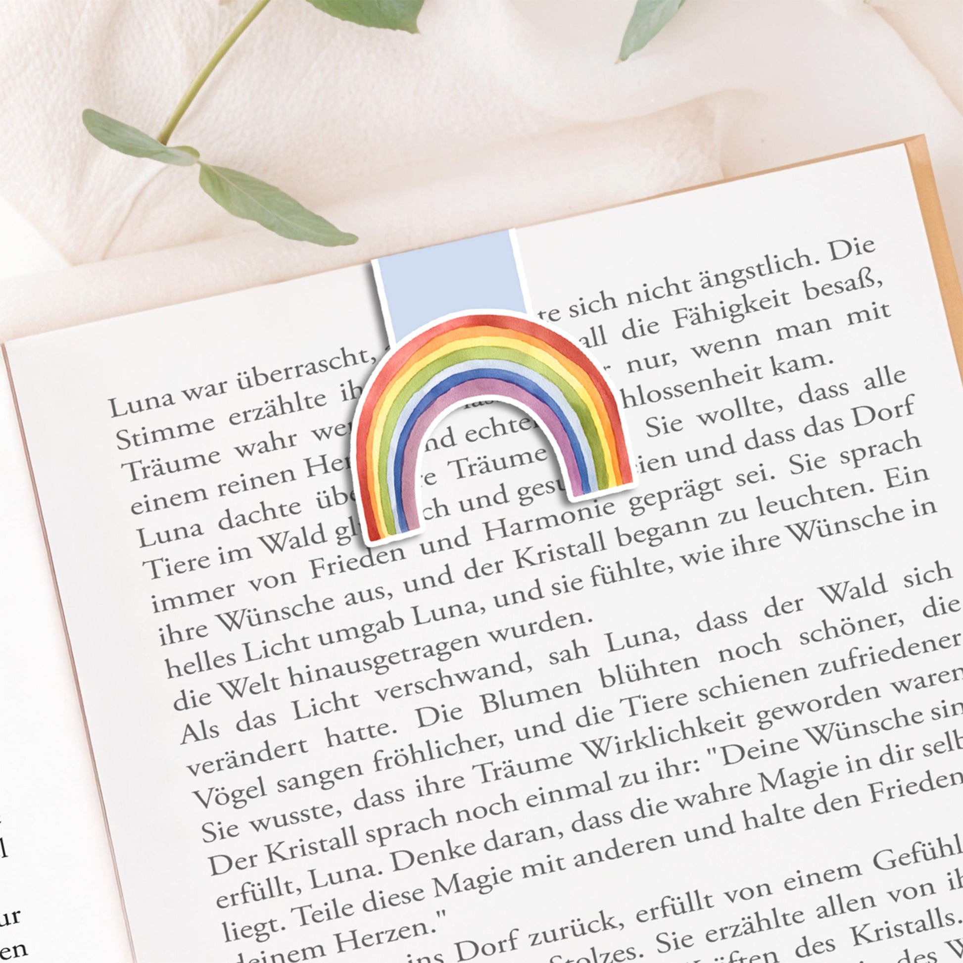 Magnetisches Lesezeichen Regenbogen blau: Handgemaltes Regenbogenmotiv auf mattem Papier, versiegelt mit Vinyl, mit Magneten zum sicheren Halt auf Buchseiten.