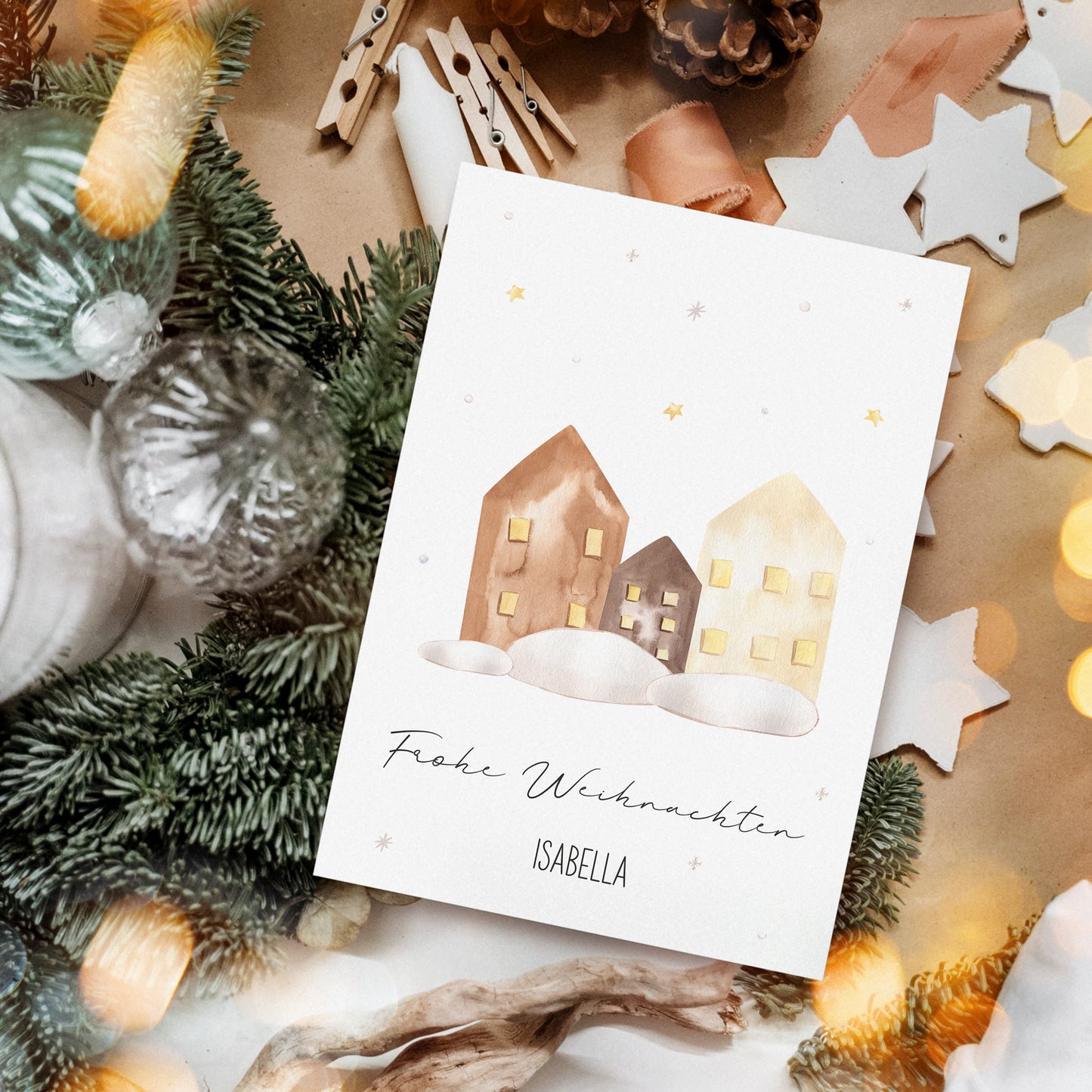 Personalisierte Weihnachtskarte Häuser A6 mit drei schneebedeckten Häusern und Frohe Weihnachten umgeben von festlichen Dekorationen wie Tannenzweigen, Glasbaubles und Kerze.