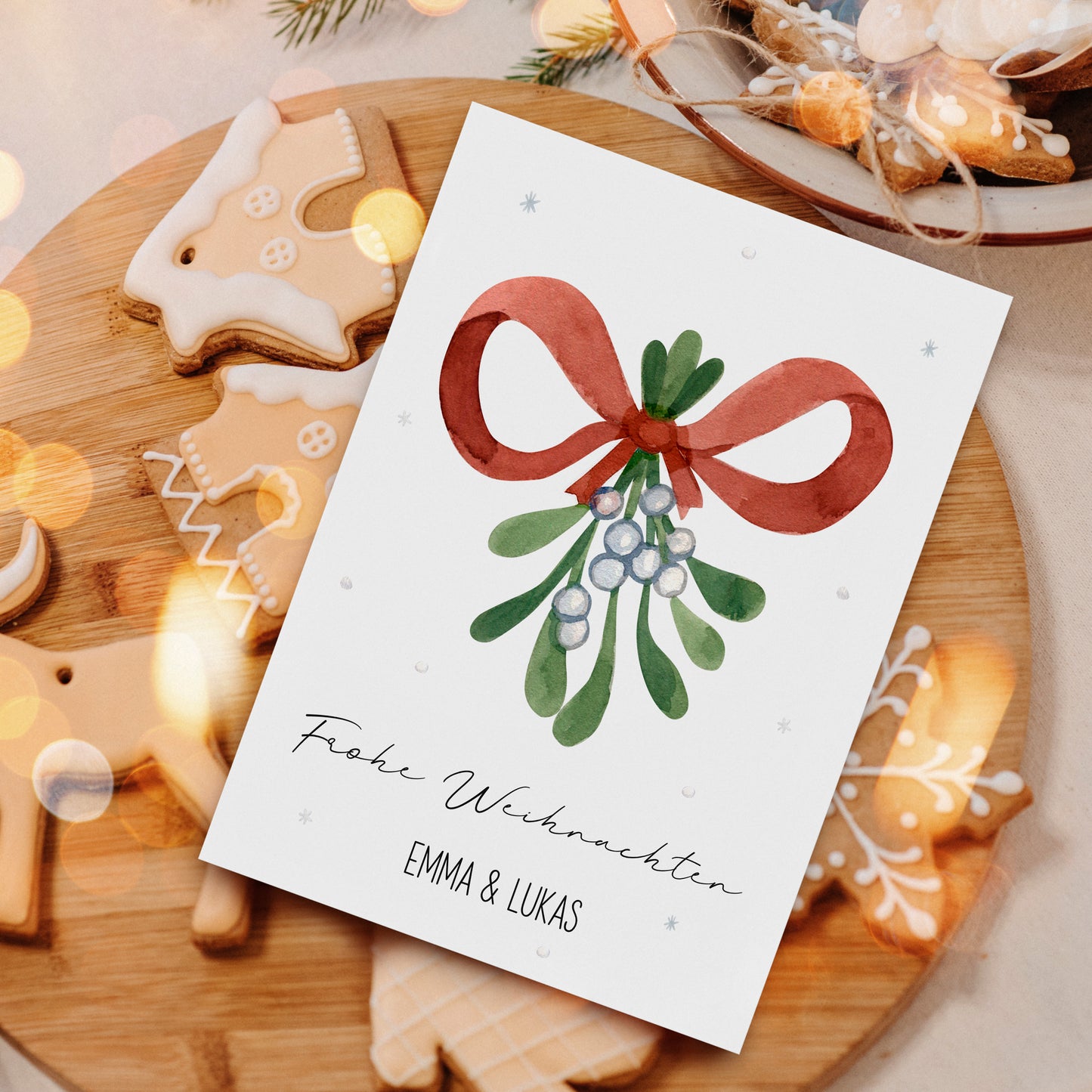 Personalisierte Weihnachtskarte Mistelzweig A6 mit handgemaltem Mistelzweigmotiv und Frohe Weihnachten Gruß, umgeben von Lebkuchen auf Holzteller, ideal für festliche Grüße.