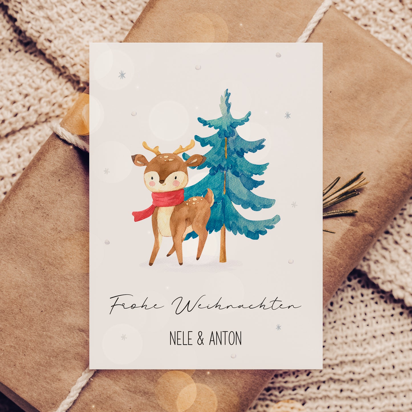 Personalisierte Weihnachtskarte Reh & Winterwald A6 zeigt ein Reh mit rotem Schal vor einem Tannenbaum, mit Frohe Weihnachten und Namen Nele & Anton.