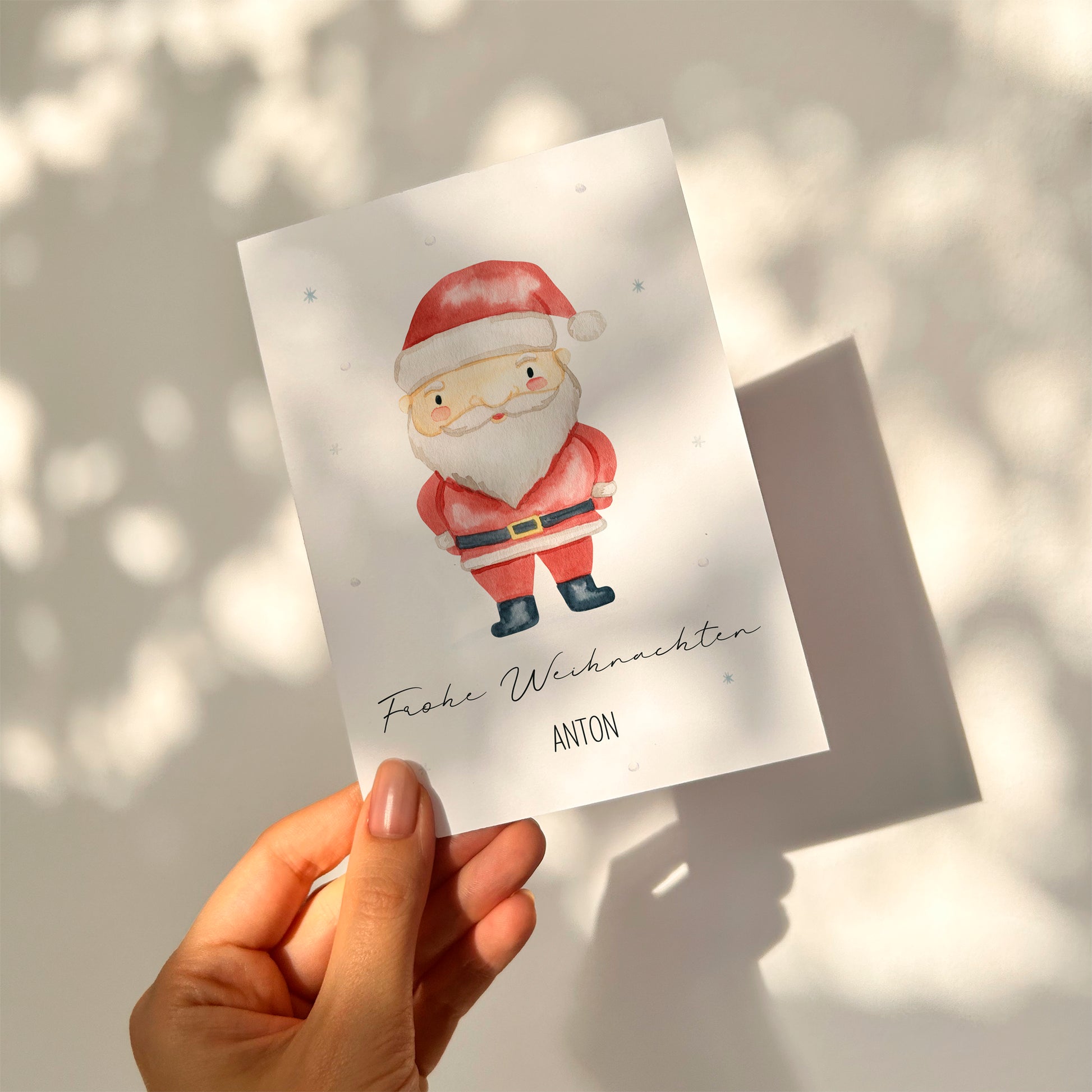 Hand hält personalisierte Weihnachtskarte A6 mit niedlichem Weihnachtsmann und Frohe Weihnachten Anton Schriftzug, perfekt für festliche Grüße oder Geschenke.