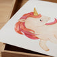 Posterset Einhorn und Schmetterling A4 & A3, zeigt eine Zeichnung eines Einhorns auf einer Holzbox; ideal für Kinderzimmerdeko oder als Geschenk.