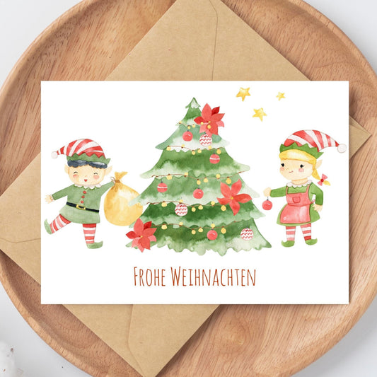 Weihnachtskarte Elfen & Weihnachtsbaum Frohe Weihnachten A6: Karte mit Elfen, Weihnachtsbaum, Frohe Weihnachten-Schriftzug auf hochwertigem Naturpapier, ideal für Weihnachtsgrüße.