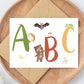 Karte ABC A6 mit bunten Buchstaben und Tieren auf einer Holzplatte, perfekt als Geschenk zum Schulanfang, gedruckt auf hochwertigem, mattem 300g Naturpapier.