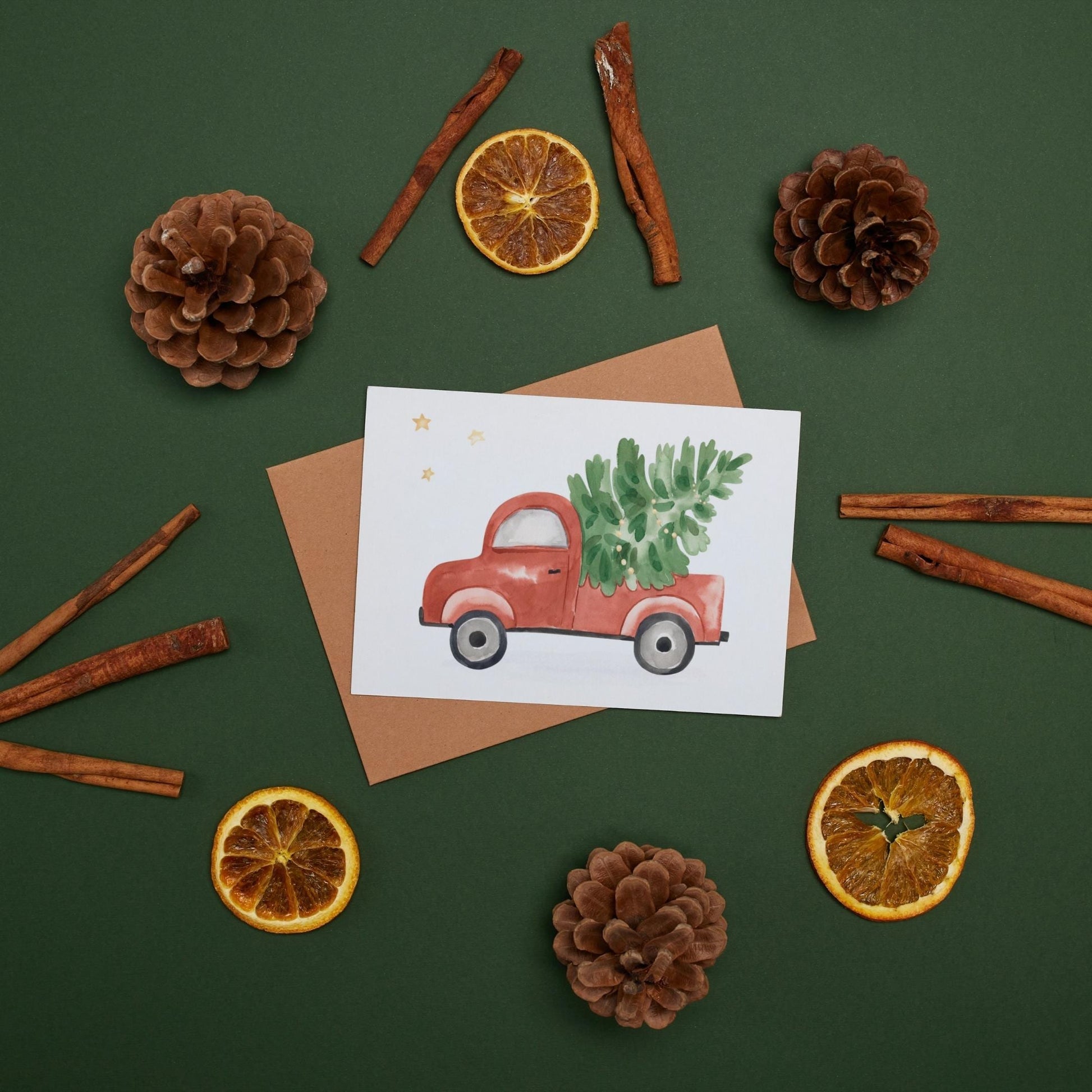 Weihnachtskarte Auto & Weihnachtsbaum A6 mit rotem Truck, Weihnachtsbaum. Auf grünem Untergrund mir getrockneten Orangen. Gedruckt auf hochwertigem, mattem Naturpapier.