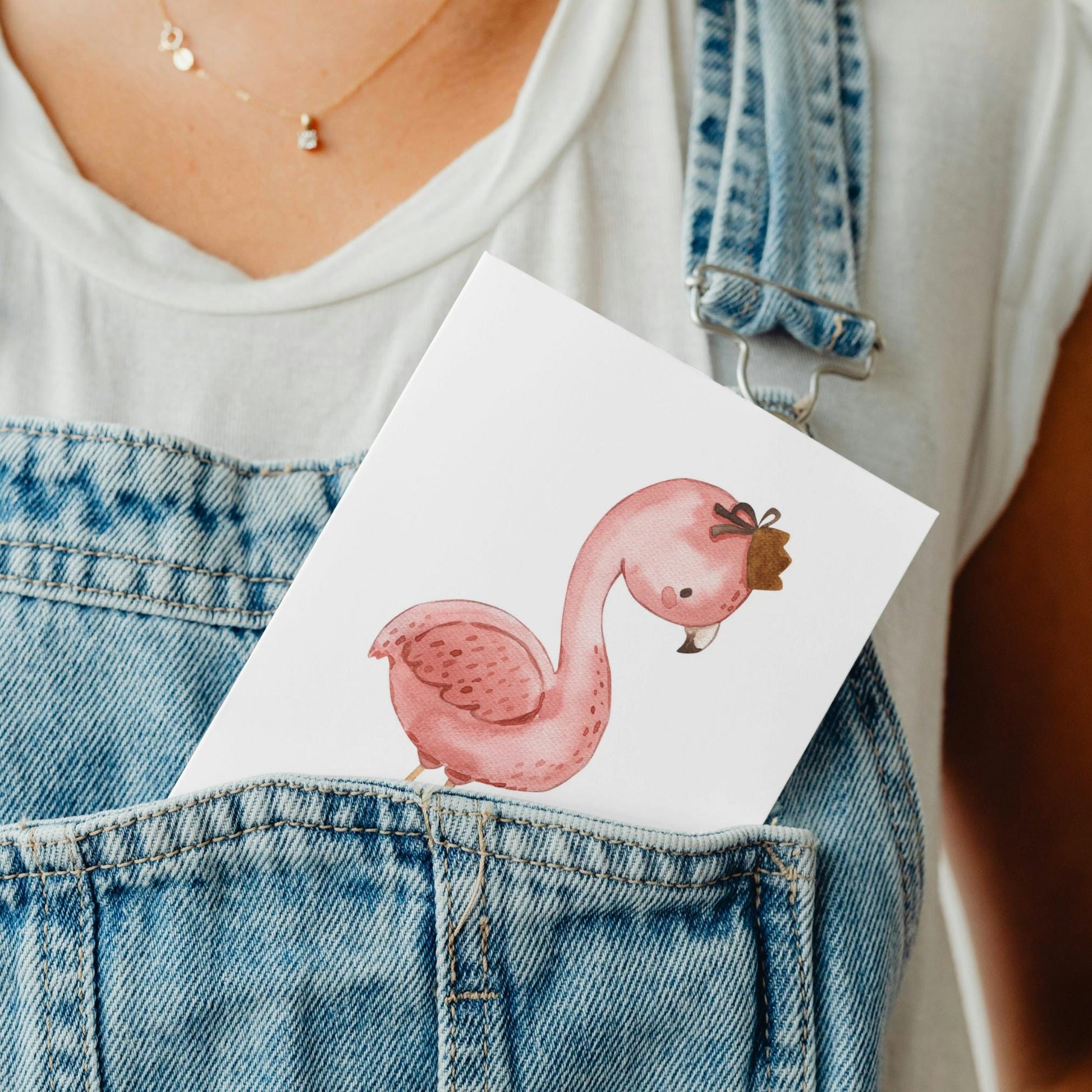 Person hält Karte Flamingo Vintage A6 mit niedlichem Flamingo-Design in blauer Latzhose, ideal für Kindergeburtstage. Hochwertiges Naturpapier, handgefertigt in Deutschland.