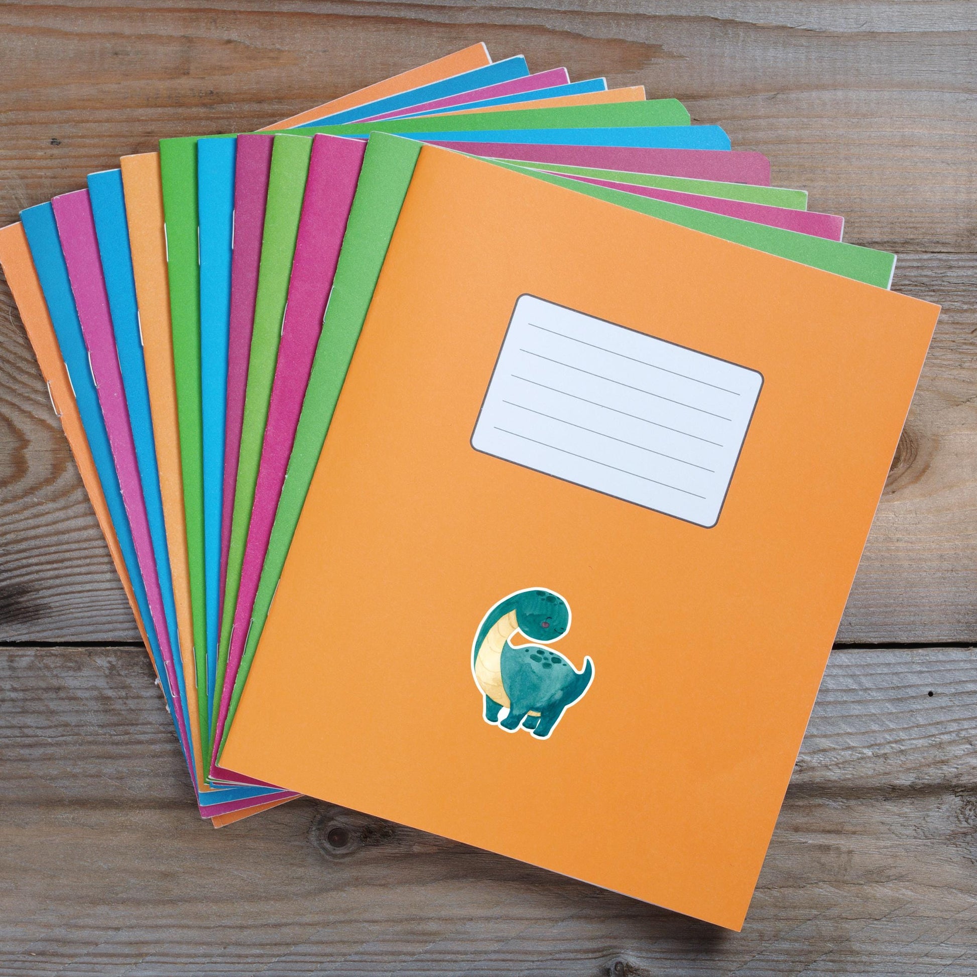 Sticker Dinosaurier dunkelgrün: Handgemalter Dino-Vinyl-Sticker auf einem bunten Notizbuchstapel, ideal für Bullet Journals und individuelle Dekorationen. Spritzfest und langlebig.